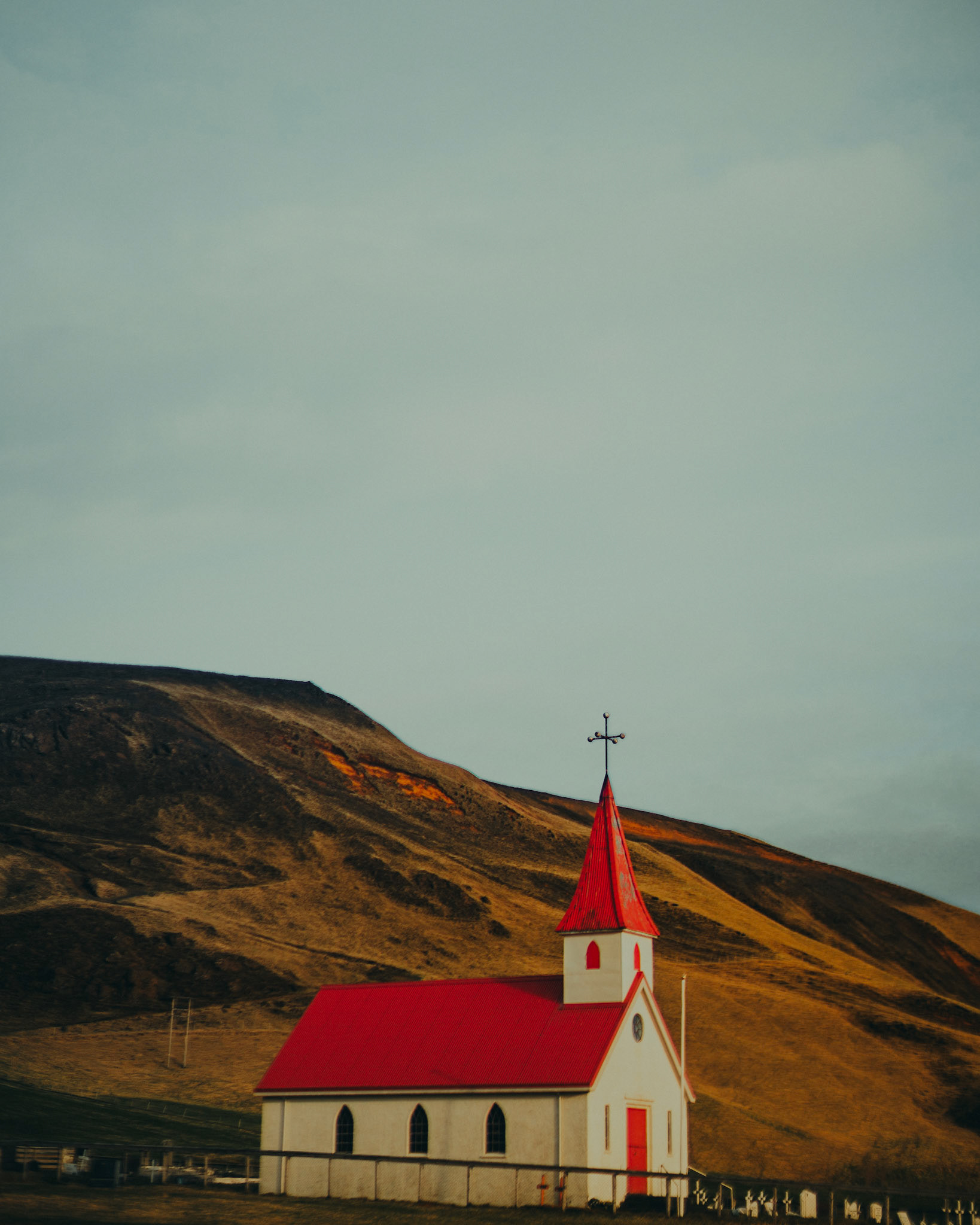 Reyniskirkja Church with a bright orange roof and a prominent steeple near Vik, Iceland, May 2016, Sony A7RII.