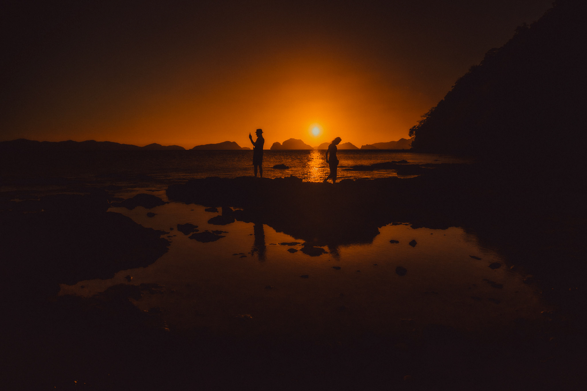 Golden hour moody travel couple silhouettes, just minutes before sunset, Las Cabanas Beach, El Nido, Palawan, Philippines, Southeast Asia, February 2019, Sony A7III.