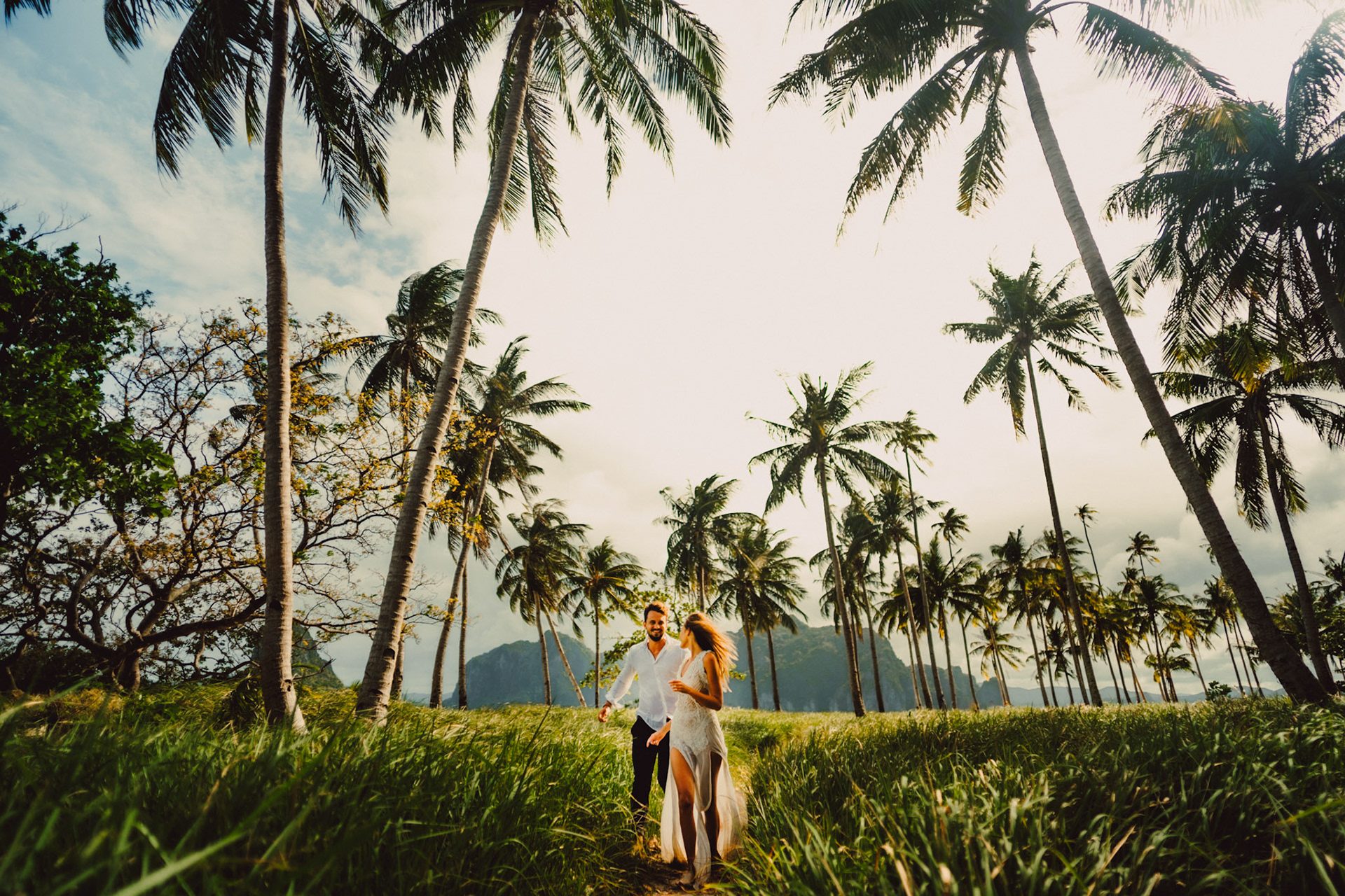 Travel couple portraits with a tropical vibe, palm trees and knee-high cogon grass, Pinagbuyutan Island, El Nido, Palawan, Philippines, Southeast Asia, December 2019, Sony A7III.