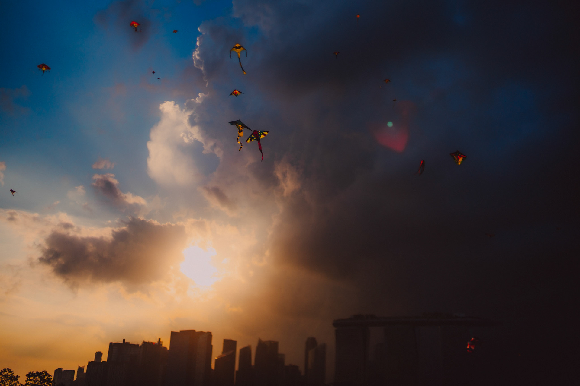 Travel photos of Singapore: Kites flying above the Singapore skyline, shortly before sunset. Marina Barrage, Singapore. March 2019.