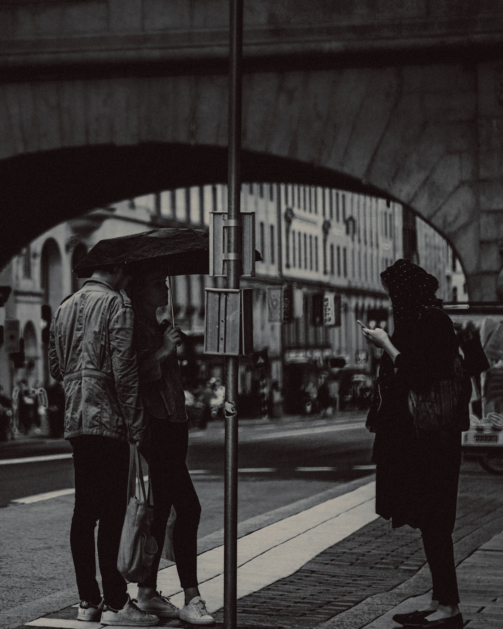 An estranged couple sharing an umbrella, in black and white, Stockholm, Sweden, July 2016, Leica M.