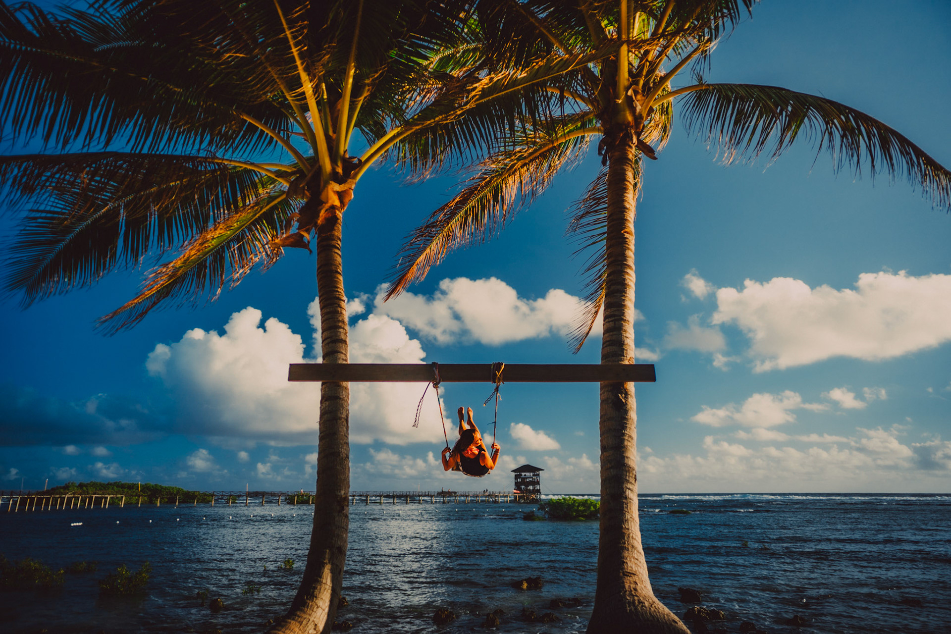 A caucasian girl on a swing in between two coconut trees, Shaka Cafe, General Luna, Siargao Island, Philippines, March 2019, Sony A7III.