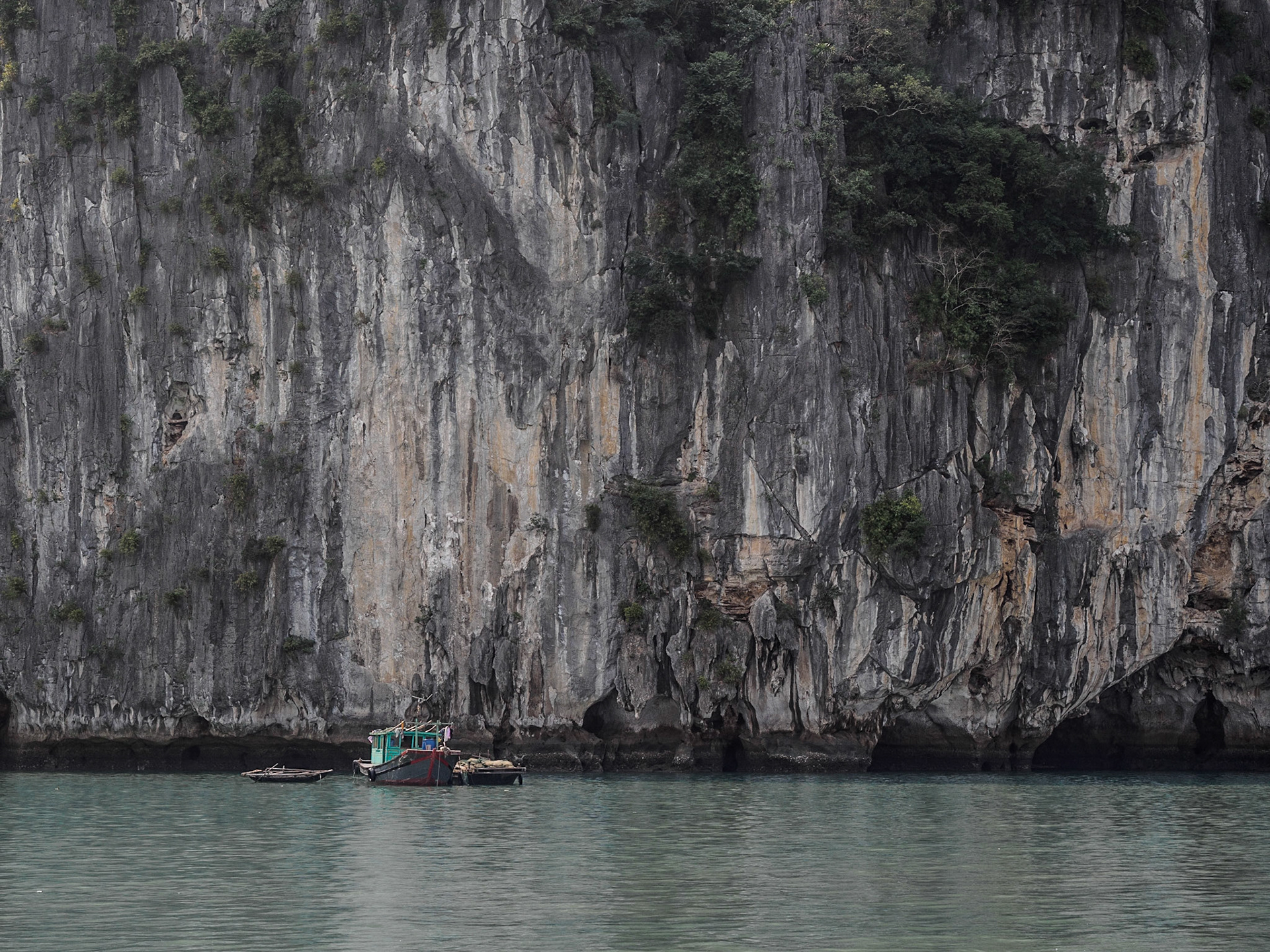 Boot vor einem mächtigen Felsen der Halong-Bucht in Vietnam