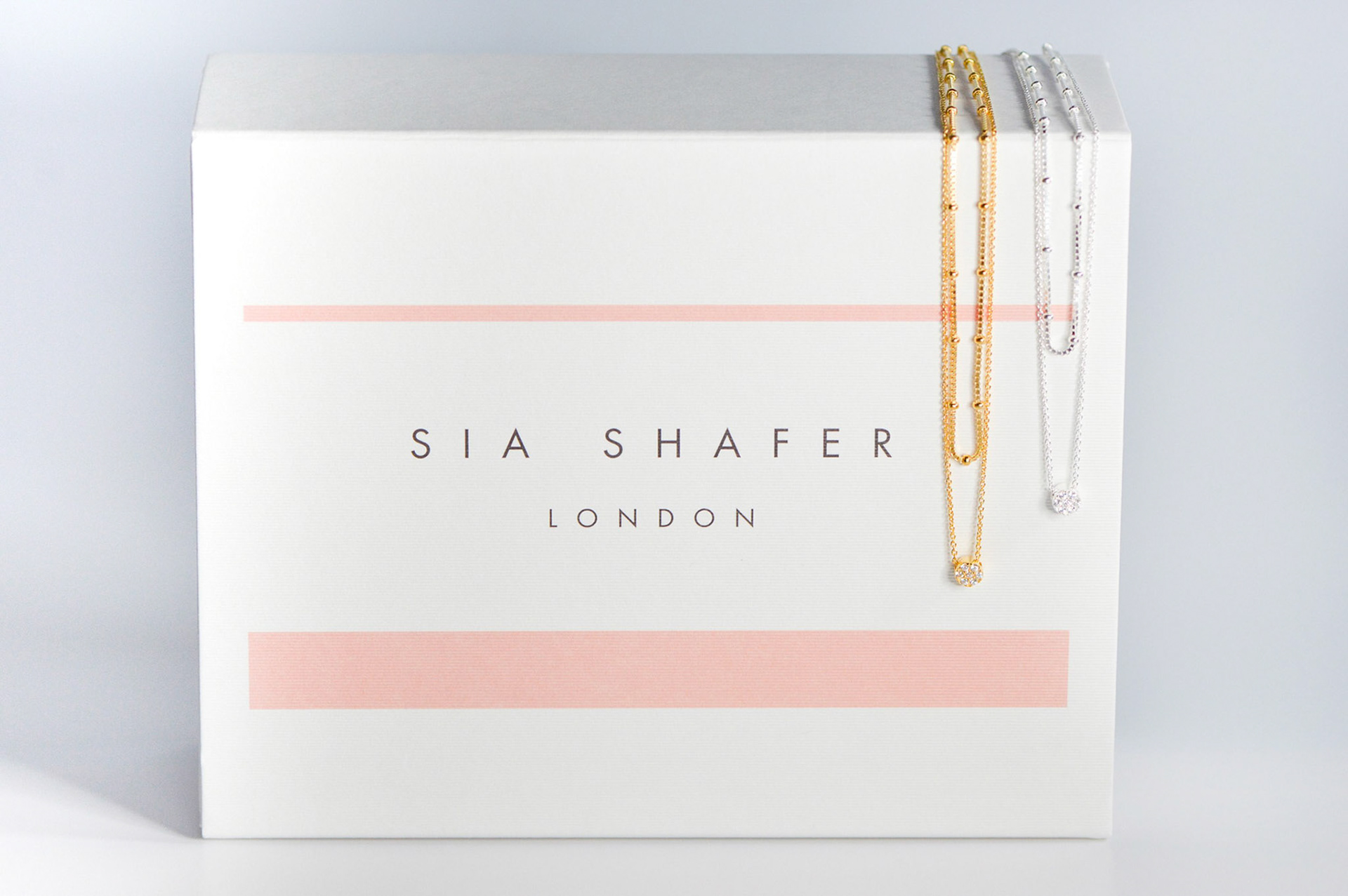 Sia Shafer gold and silver necklaces on top of packaging box creative photography