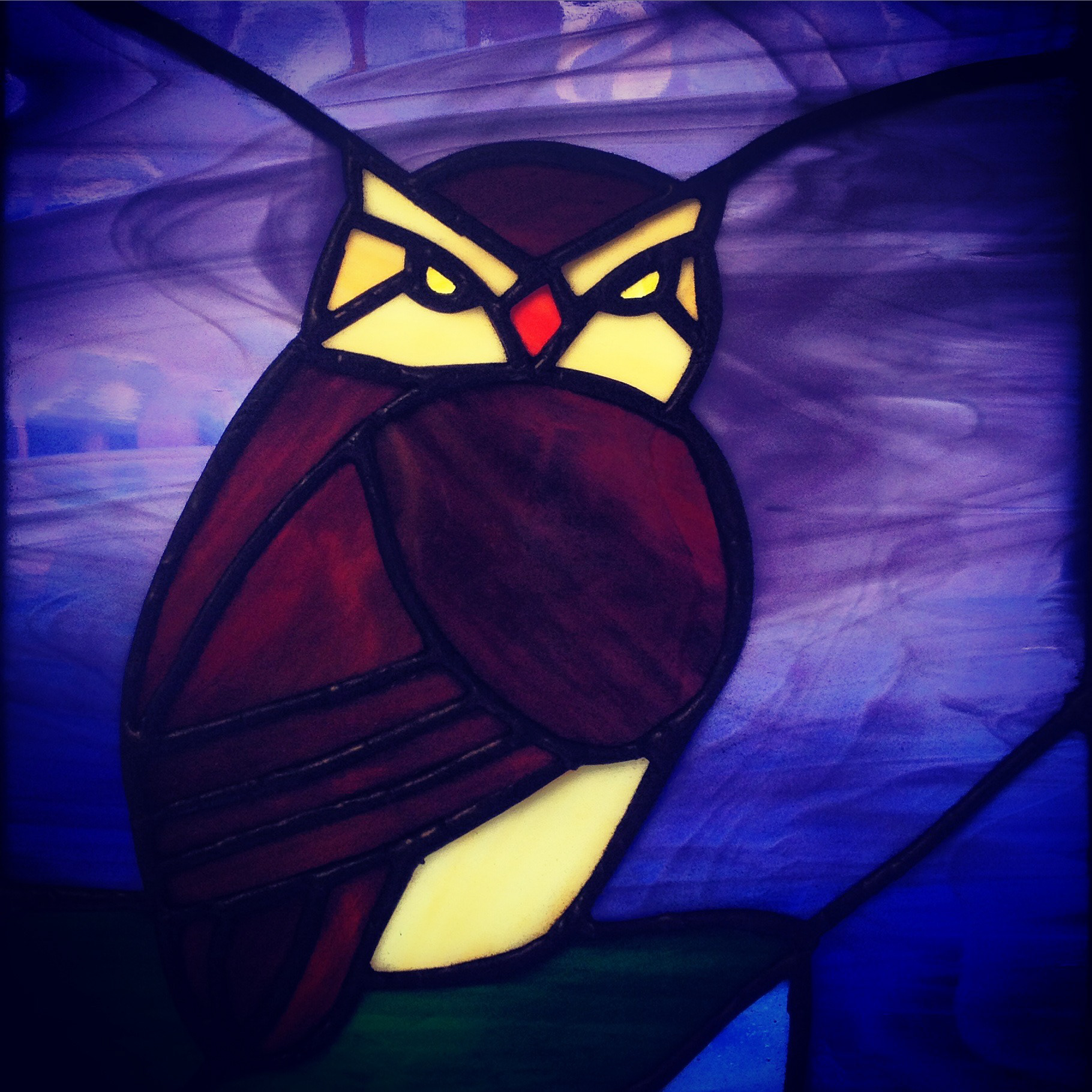 Stained glass owl, Art glass commissioned piece comprising of traditional glass, lead, solder and cement. Spectrum whispy blue background with handblown streaky brown. An owl sitting on a cliff top.