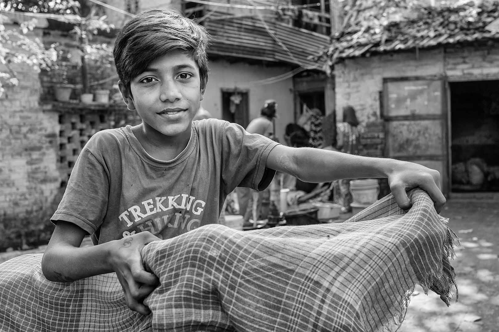 Portrait of a young boy with his bicycle covered by a cloth