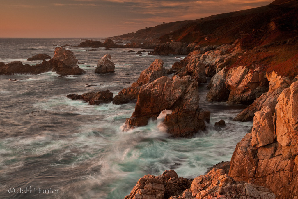 A rocky arch in the surf at sunset