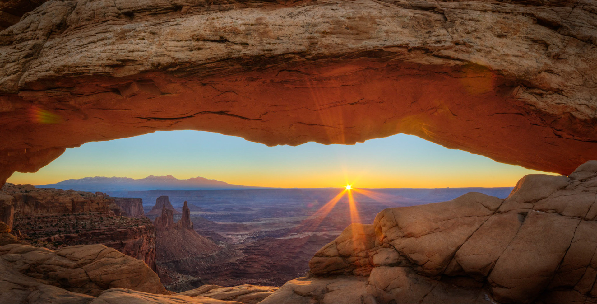 The first rays of sunlight breaking the horizon through Mesa Arch.Canyonlands National Park6 November 2014This is an HDR panoramic image consisting of 2 frames comprised of 5 exposures each. HDR processing performed in Photomatix Pro.  Panoramic stitching performed in Photoshop. Additional processing performed in Lightroom and Photoshop.PENTAX K-3, Sigma 10-20mm f/4-5.6 EX DCISO 100 18 mm  ¹⁄₁₃ sec at ƒ / 18Prints of my work are available from my website at http://www.fingolfinphoto.comFollow me on Facebook at http://www.facebook.com/fingolfinphoto or http://www.facebook.com/pesterleAlso, http://500px.com/pesterle   http://www.flickr.com/photos/fingolfinphoto