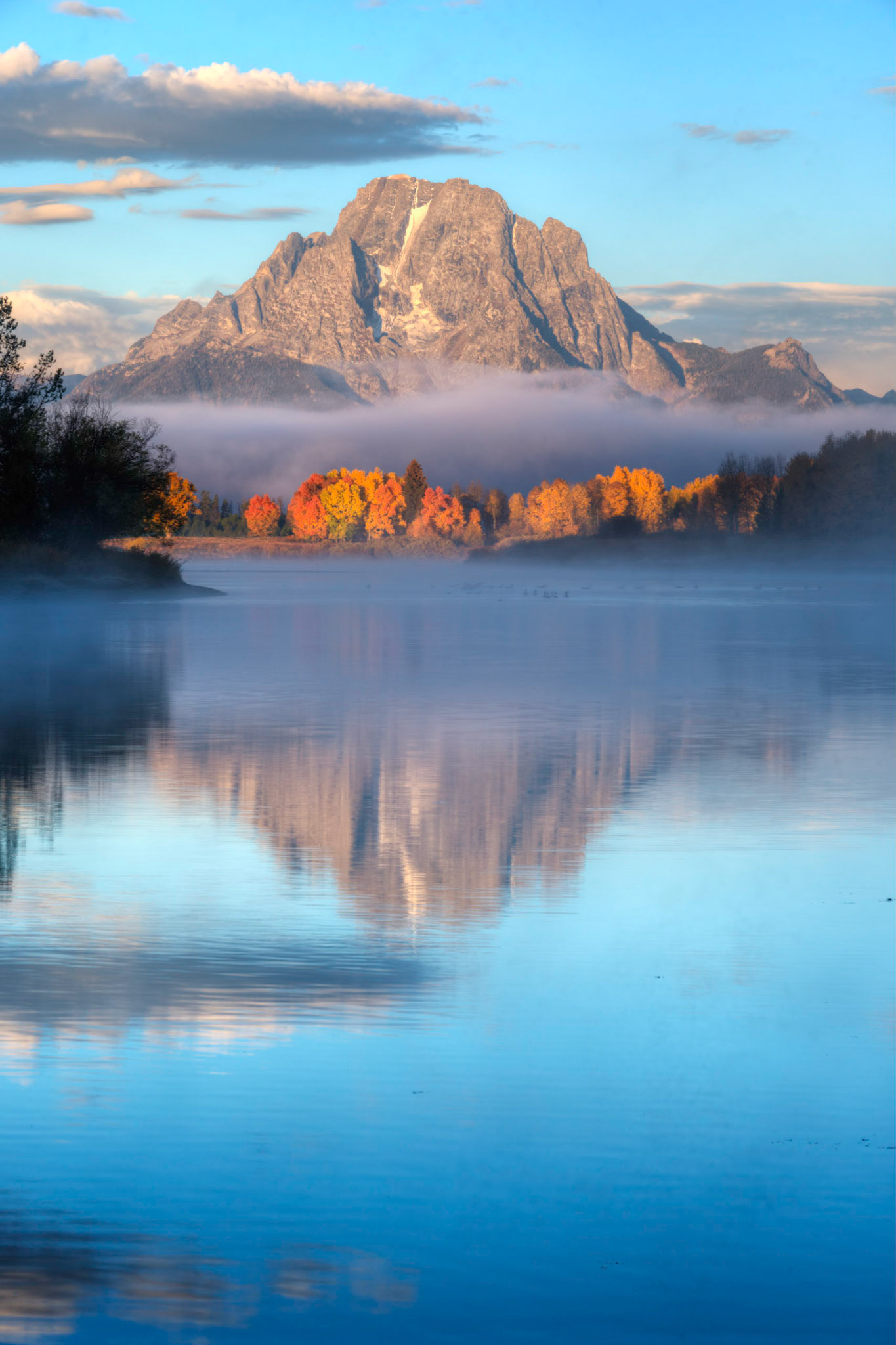 Shortly after sunrise at Oxbow Bend.  The golden light from the sun amplifies the colours of the foliage.Grand Teton National ParkWyomingOctober 1, 2016This is an HDR image consisting of 5 exposures merged in Photomatix Pro. Additional processing in Lightroom and Photoshop.PENTAX K-1, TAMRON 28-300mm F3.5-6.3 Ultra zoom XRISO 100 100 mm  ¹⁄₂₅ sec at ƒ / 16