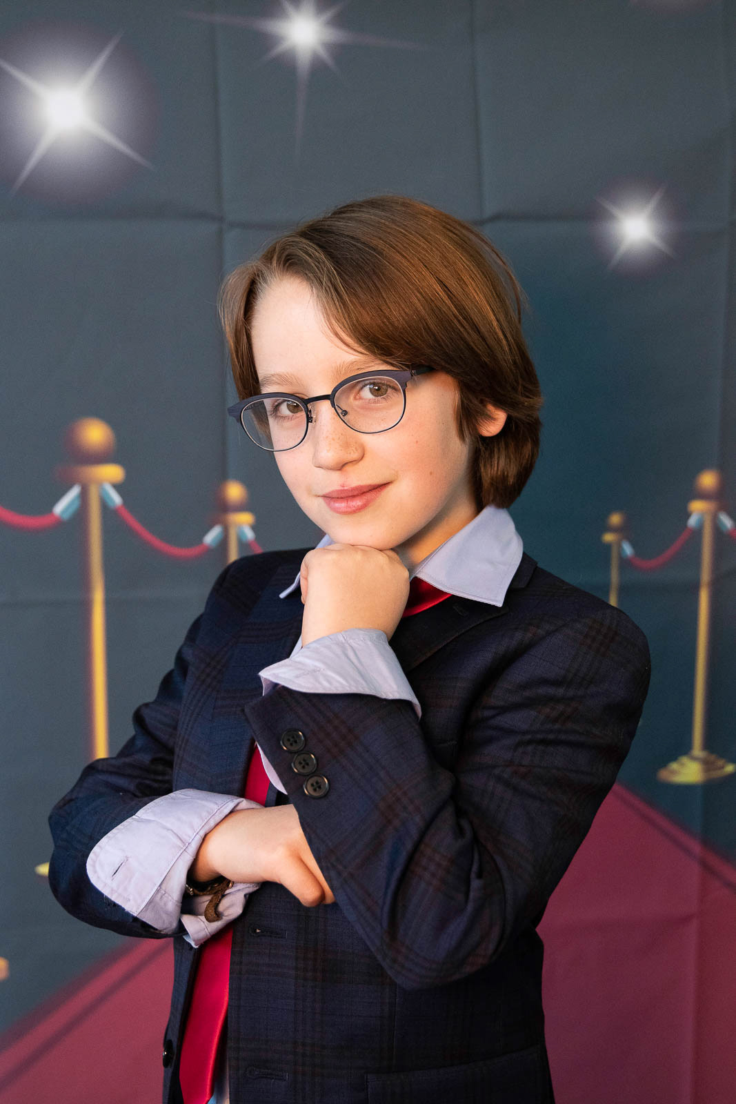 Cute young boy in glasses poses for the camera at special event