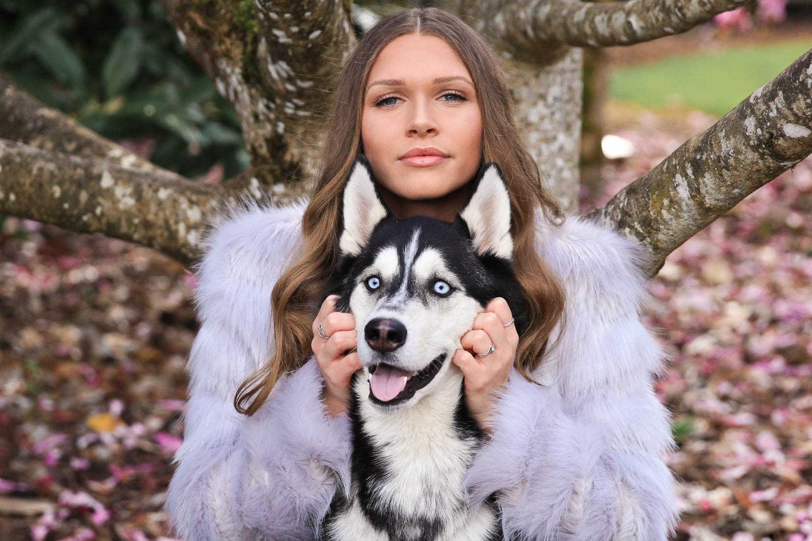 Model in fur coat poses with beautiful dog in a natural setting