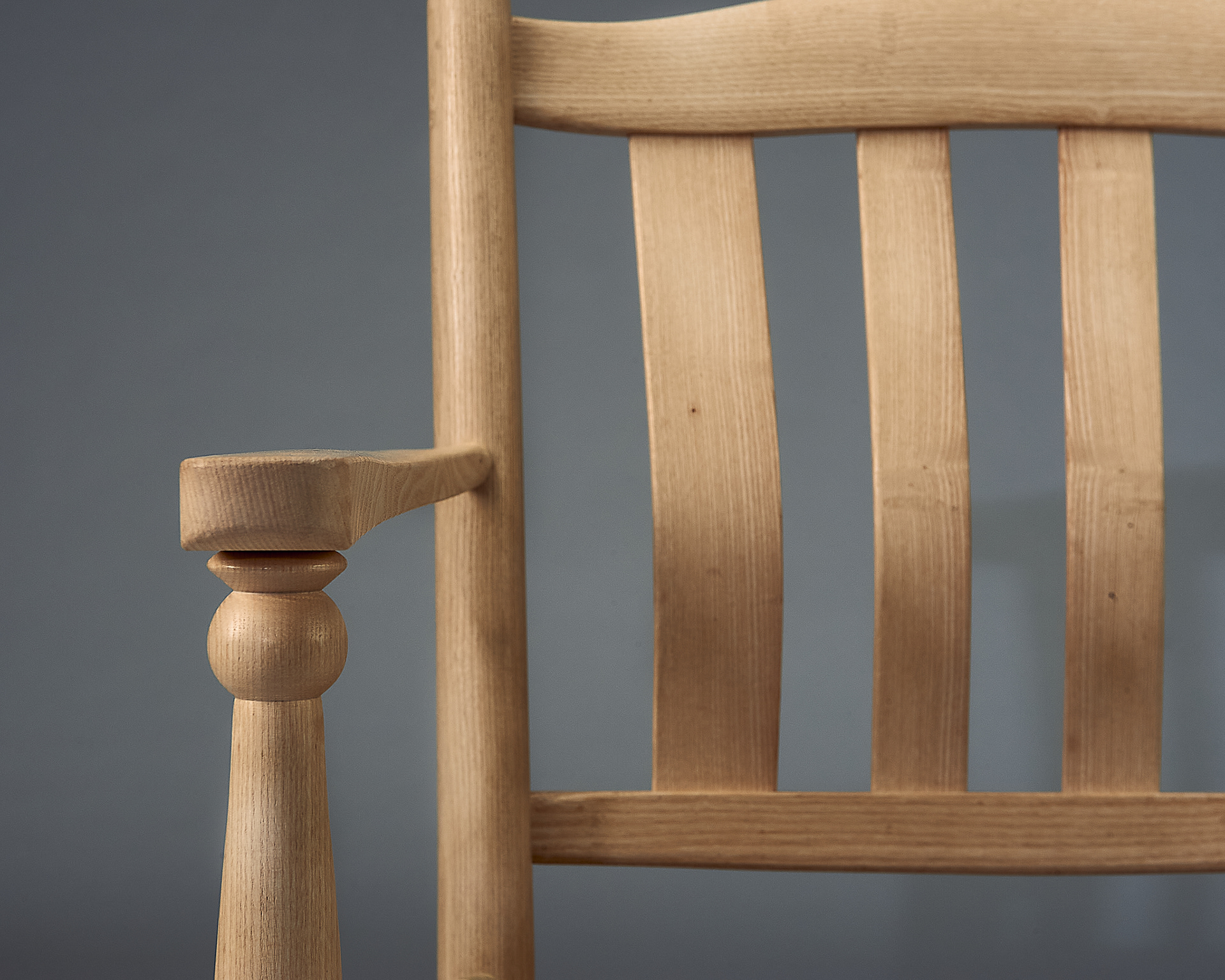 close up photo of a chair made of ash, a light-coloured wood, showing the arm detail, made by angus richardson