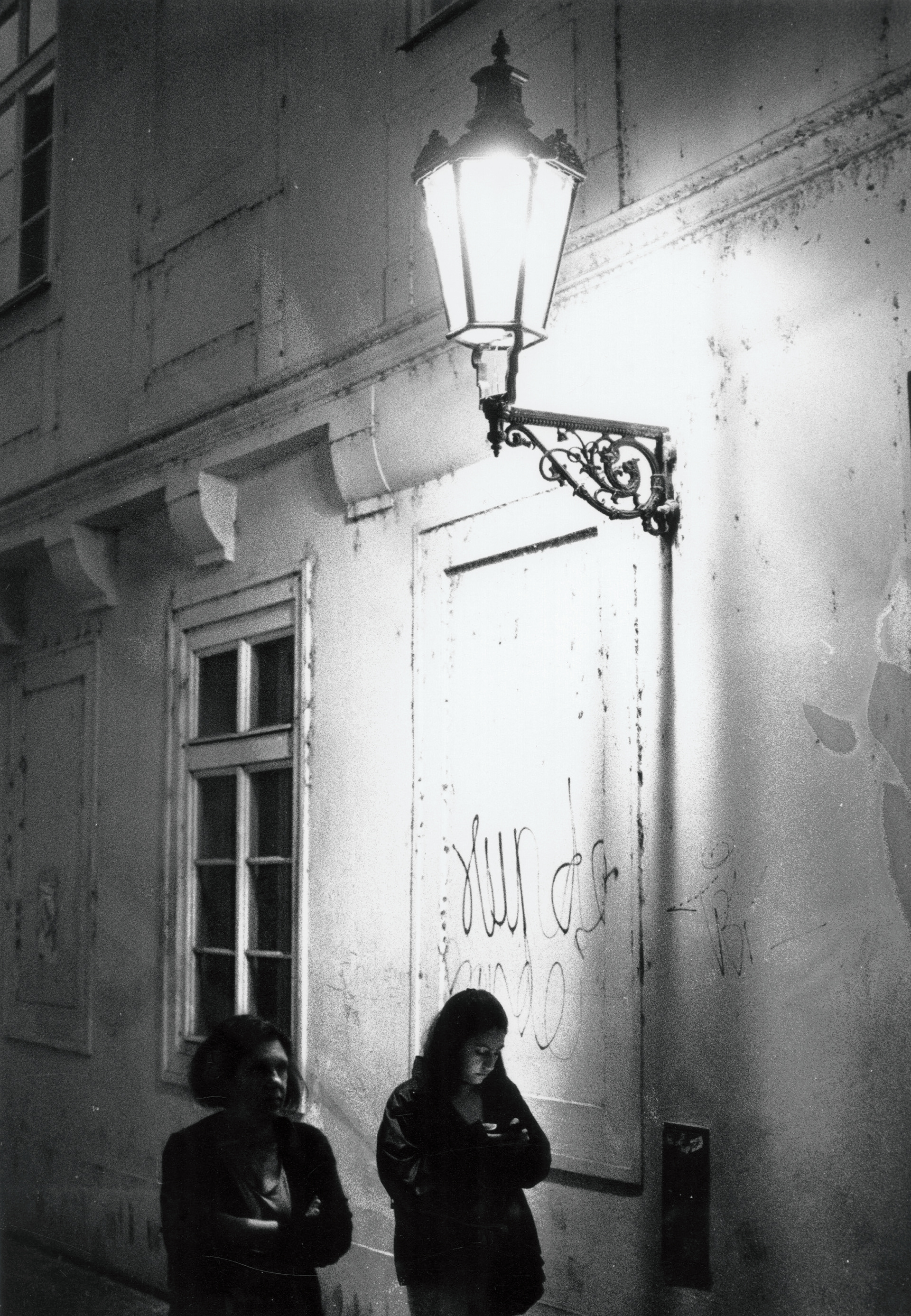 2 women walk under the bright light given off by a streetlamp in Prague
