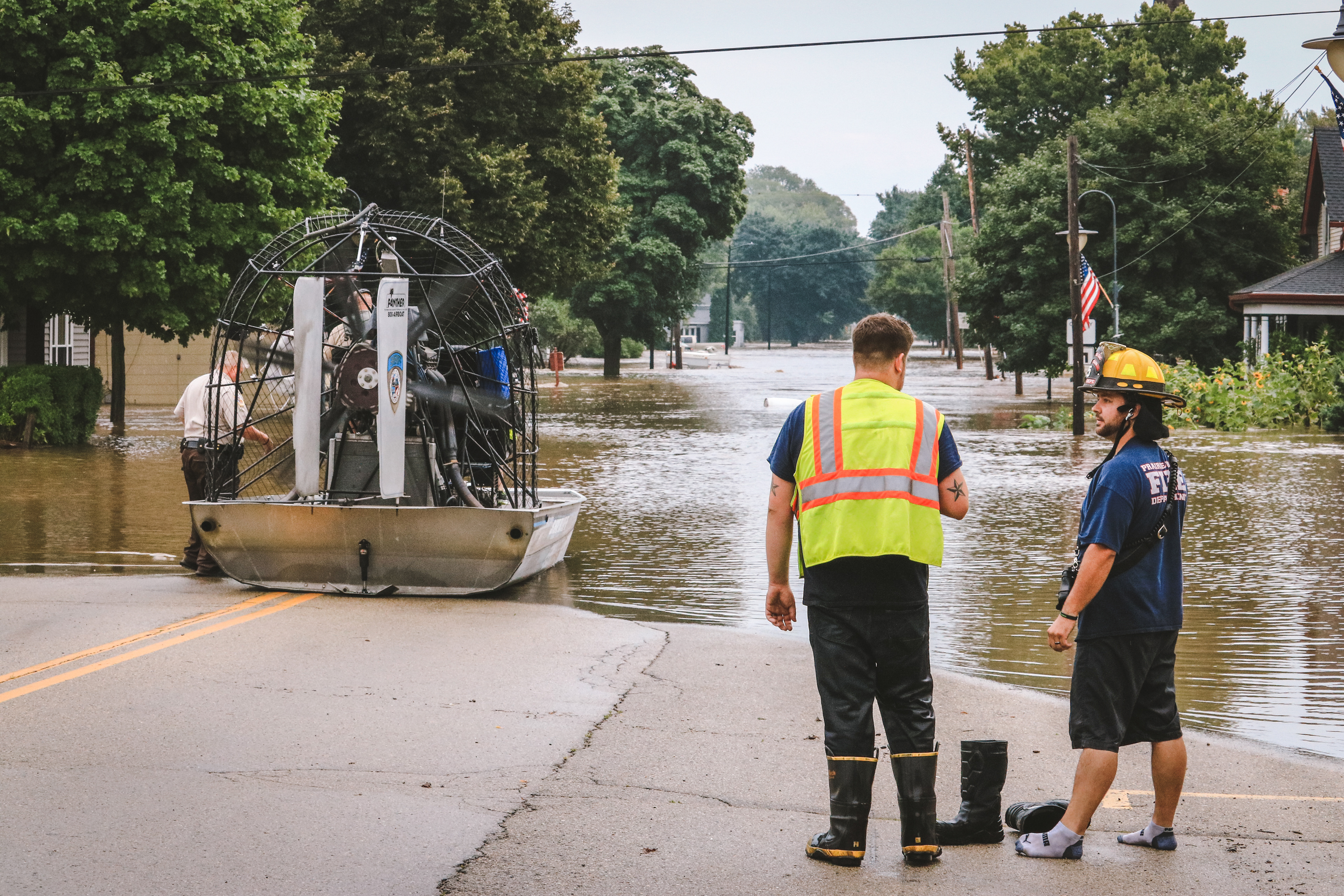 Two firefighters observe the flood waters on East Hudson Street in Mazomanie