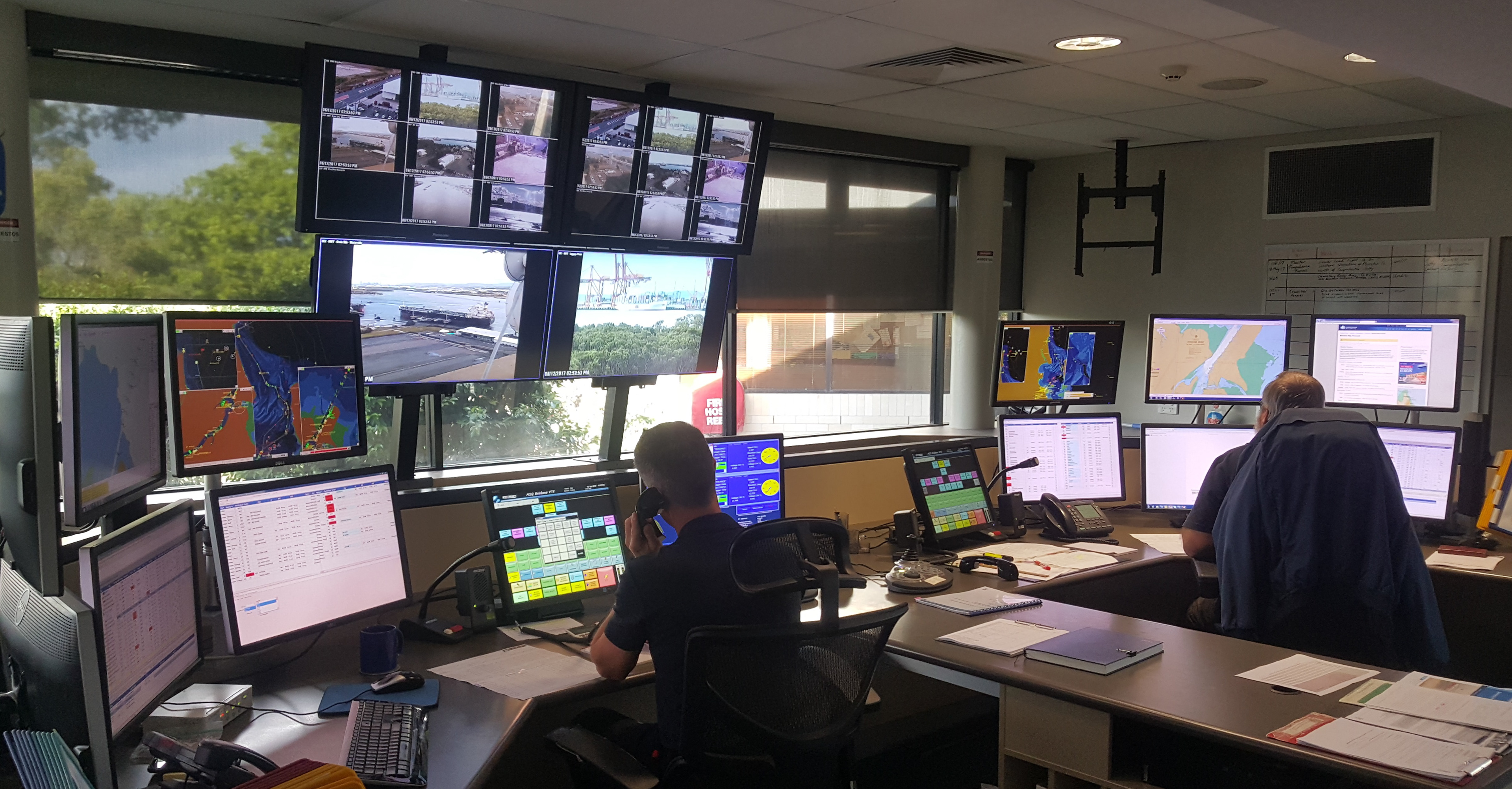 Inside vessel traffic services (VTS) centre Brisbane. Two staff members work at computer stations