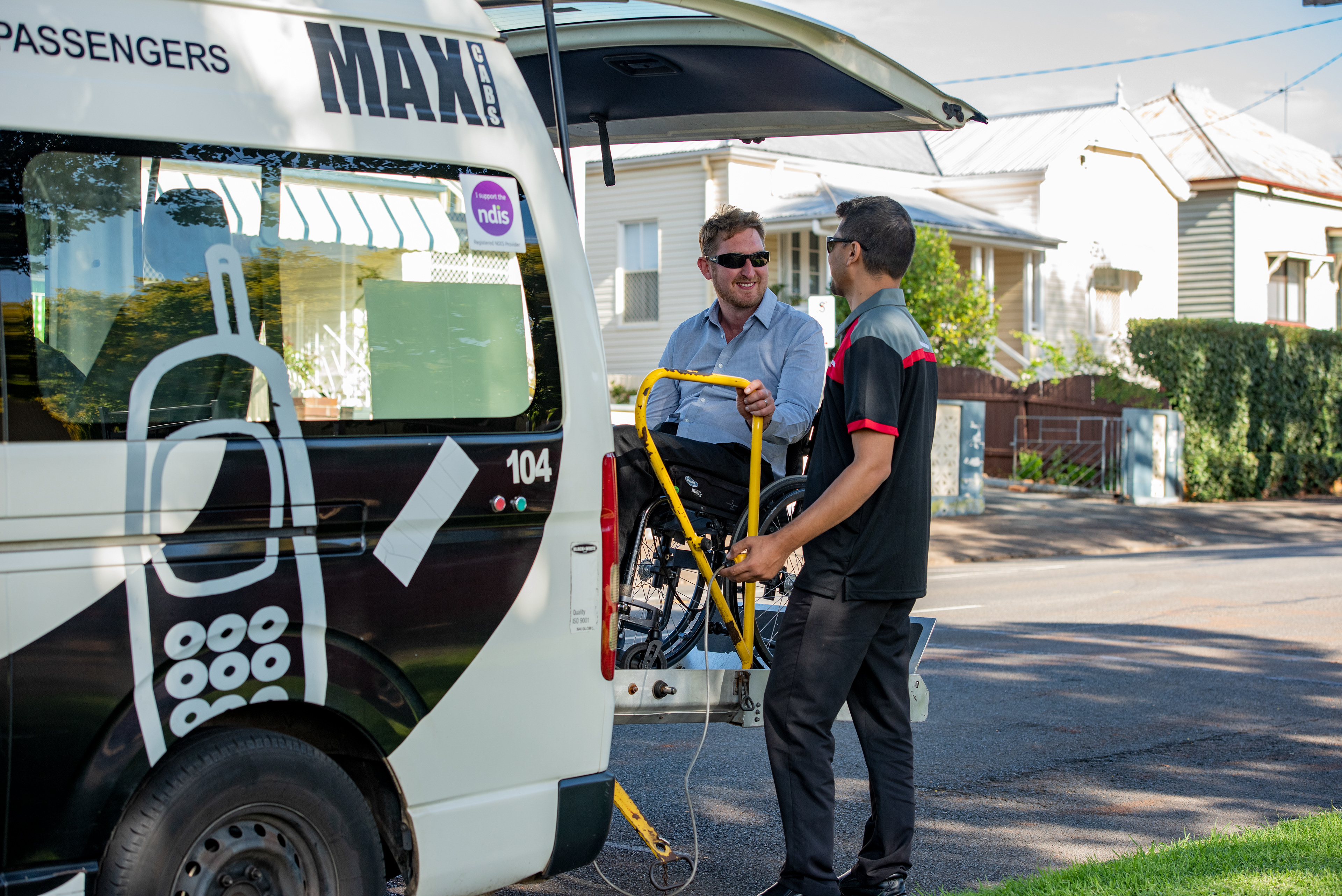 Wheelchair passenger being elevated into the rear of a maxi taxi.