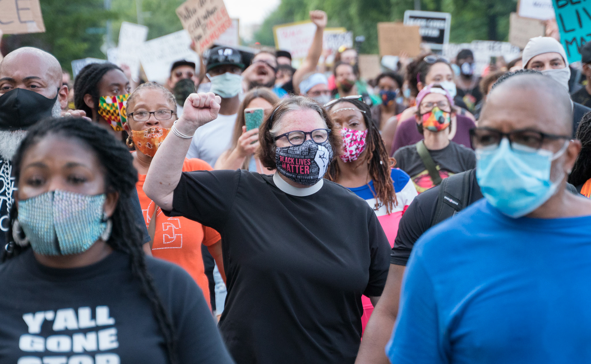A woman holds up her fist while walking down the street during a protest in the Central West End on Friday, July 3, 2020.