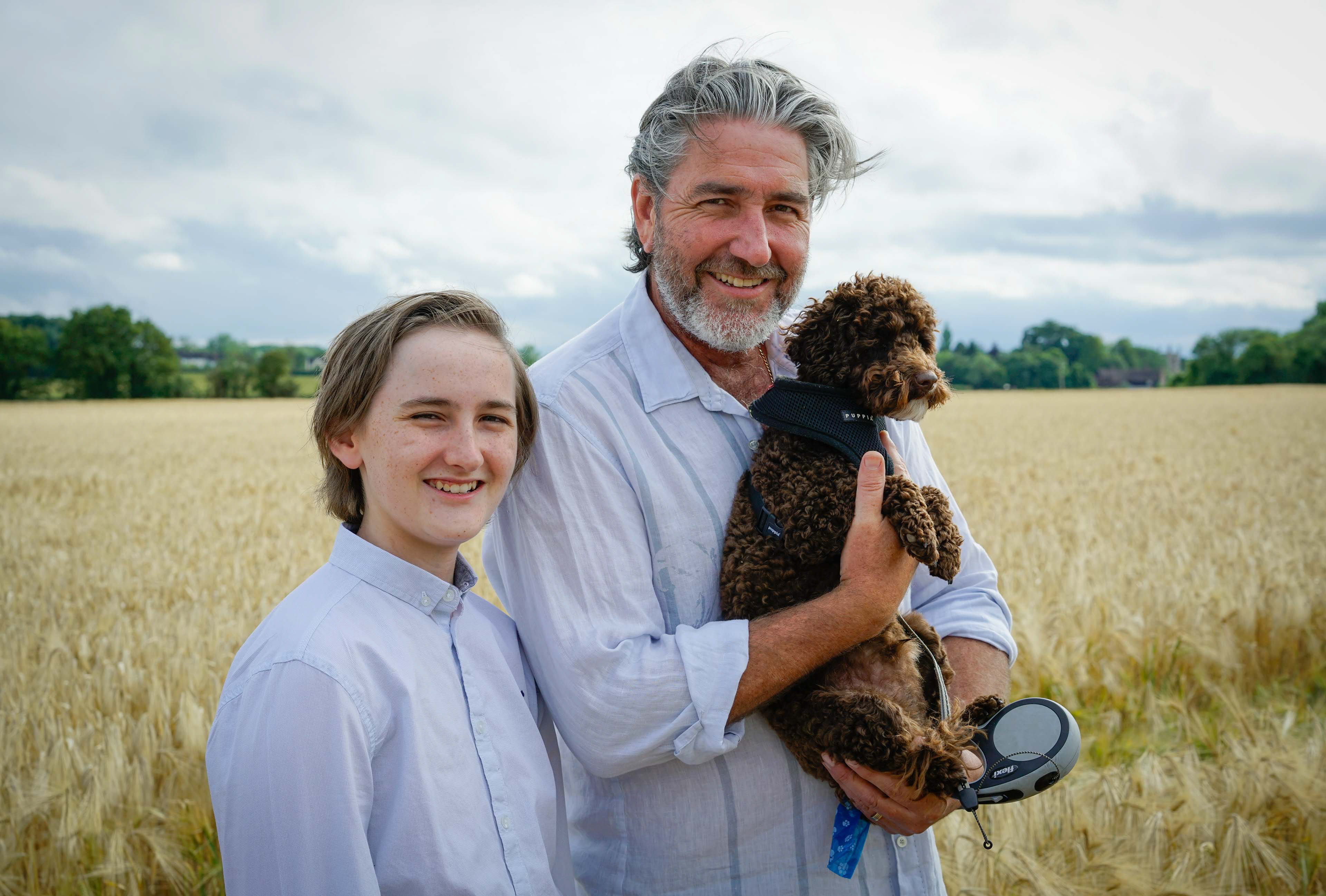 father son and dog in field