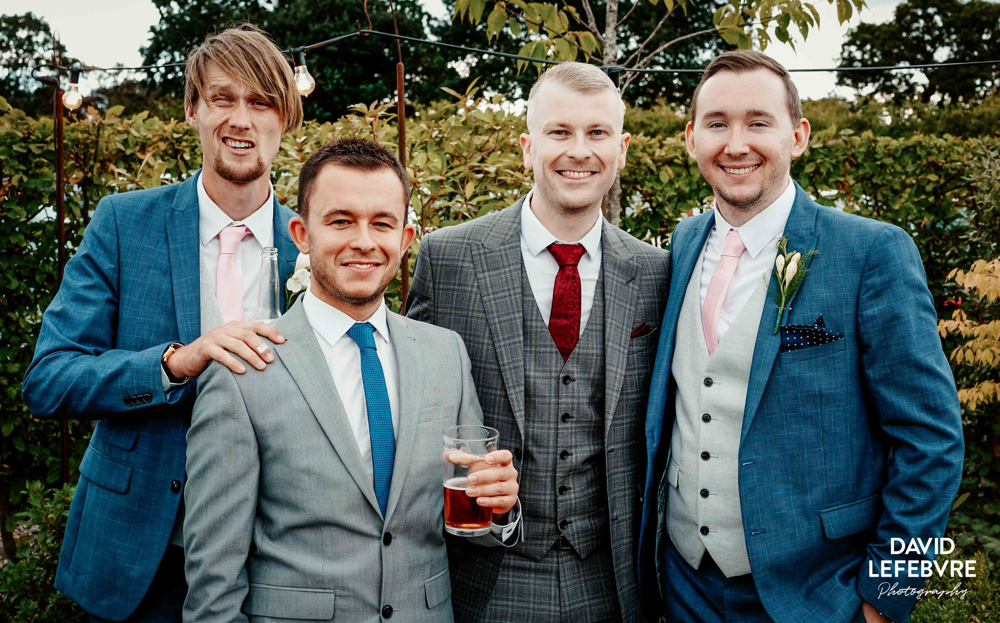 guys stood smiling with drinks at summer wedding at owen barn house