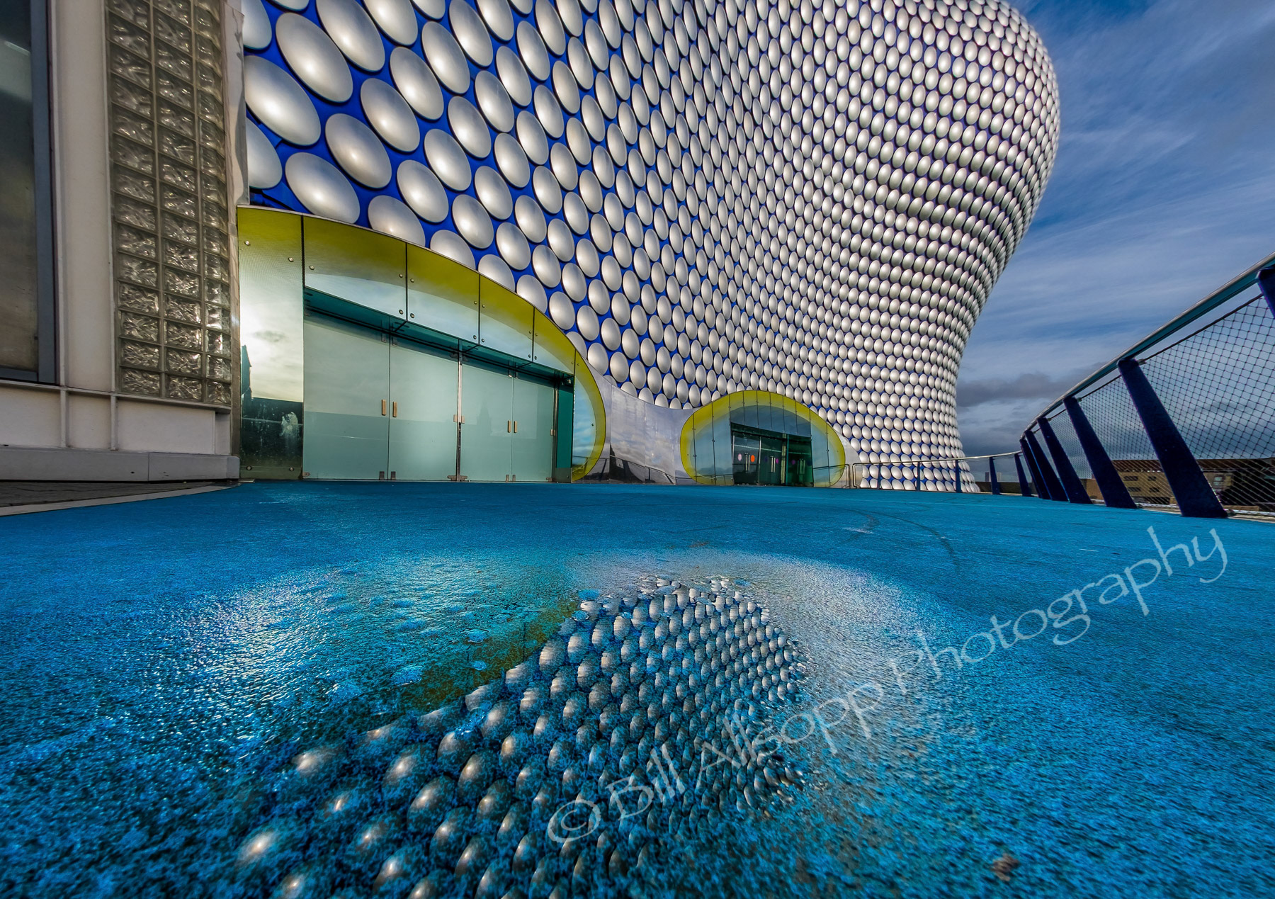The Selfridges building reflected in a puddle.
