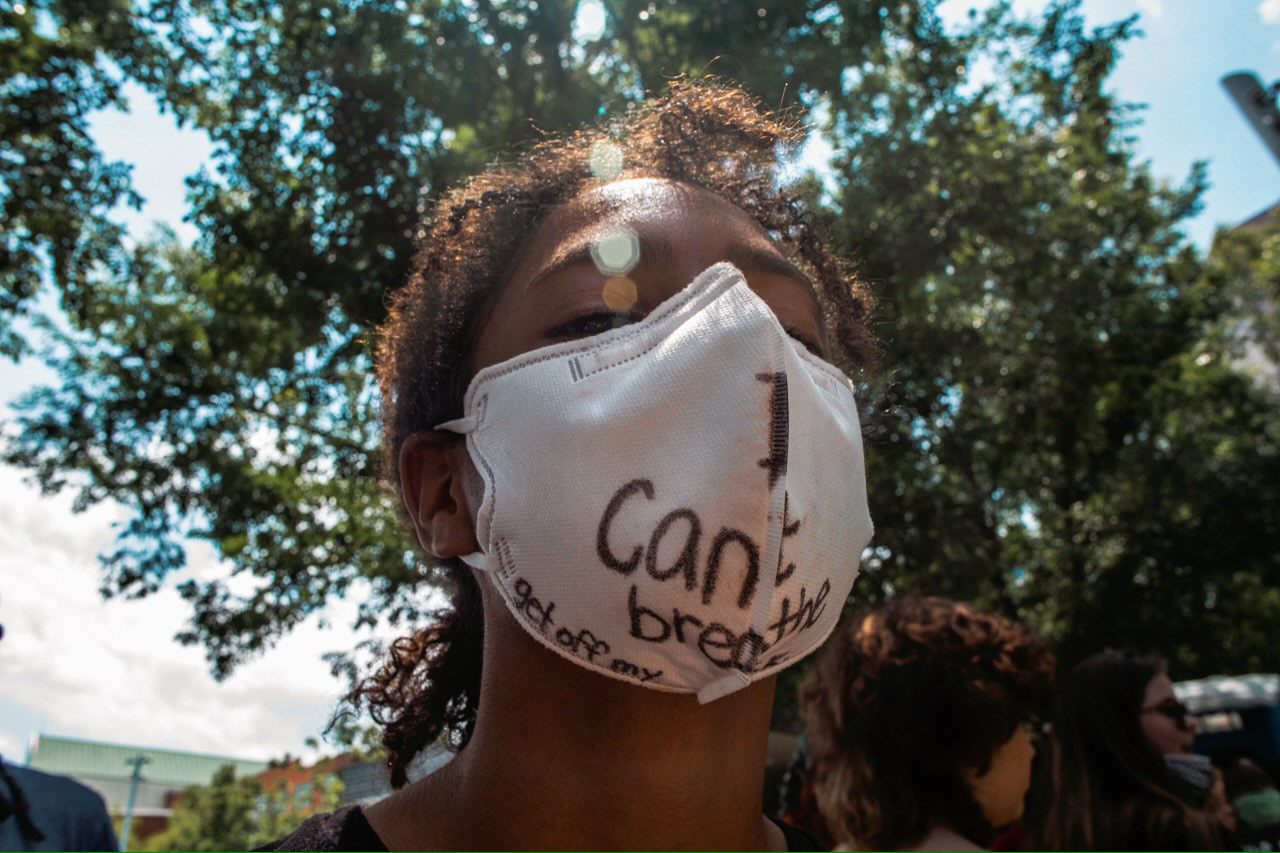 A teenage boy poses for a photo to show off his mask in which he has written "I can't breathe," the now infamous words of George Floyd as officer Derek Chauvin kneeled on his neck.