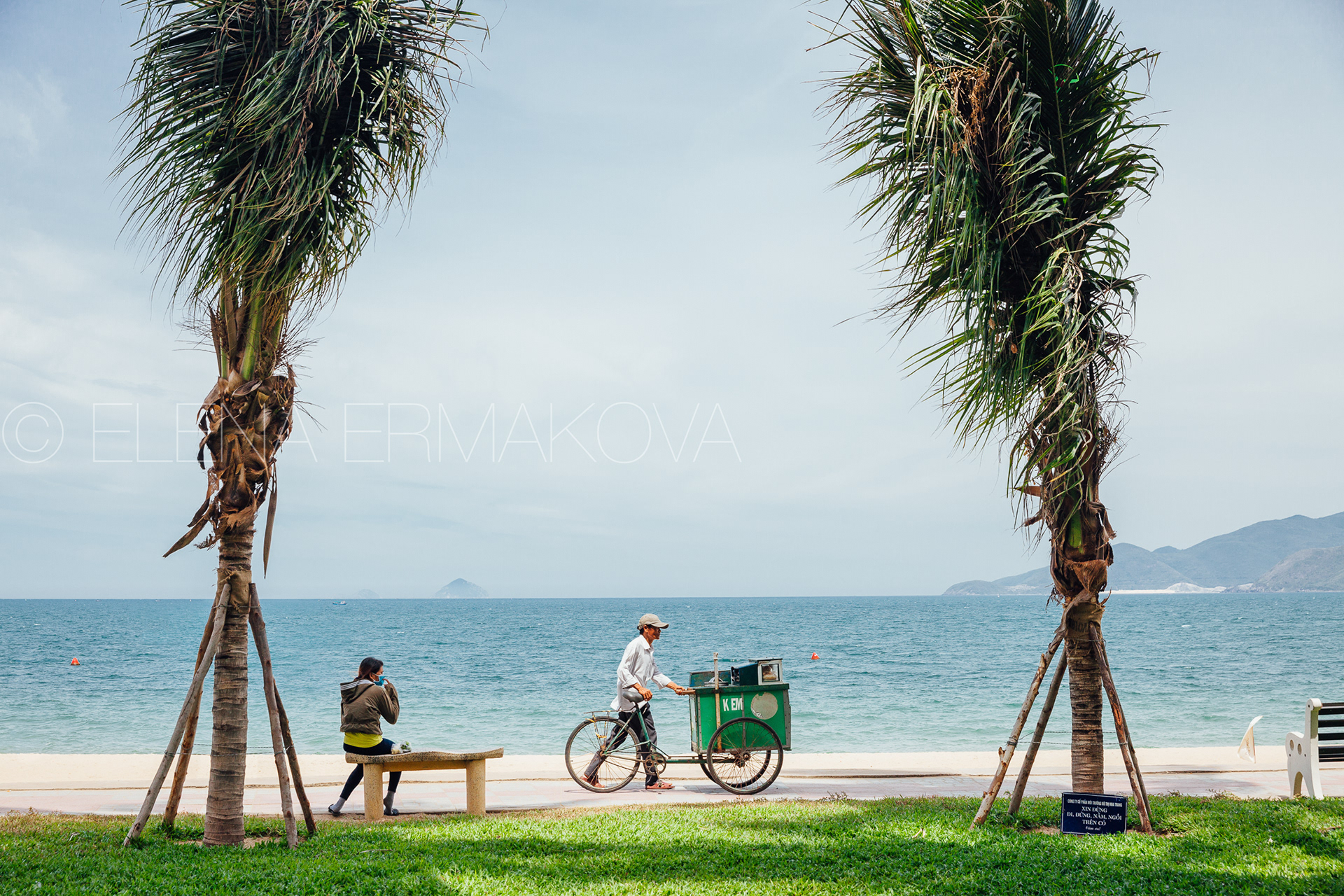 Hard workers on the beach by Elena Ermakova: Beach vendor carries goods for sale along the promenade, September 02, 2018, Nha Trang, Vietnam