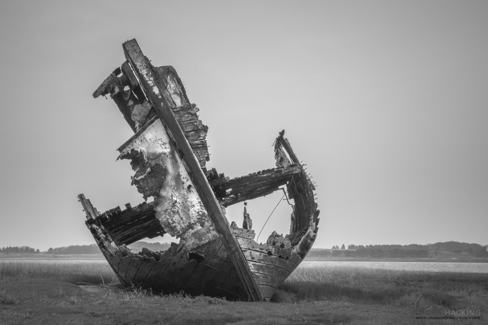 A shipwrecked fishing trawler lies on the mudflats of the River Lune Estuary at Fleetwood Marsh Nature Reserve.