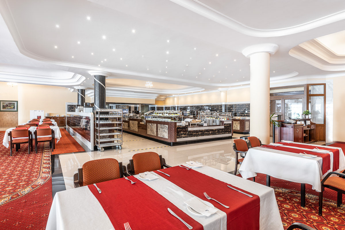 sala restauracyjna z widocznymi stołami nakrytymi czerwonymi obrusami