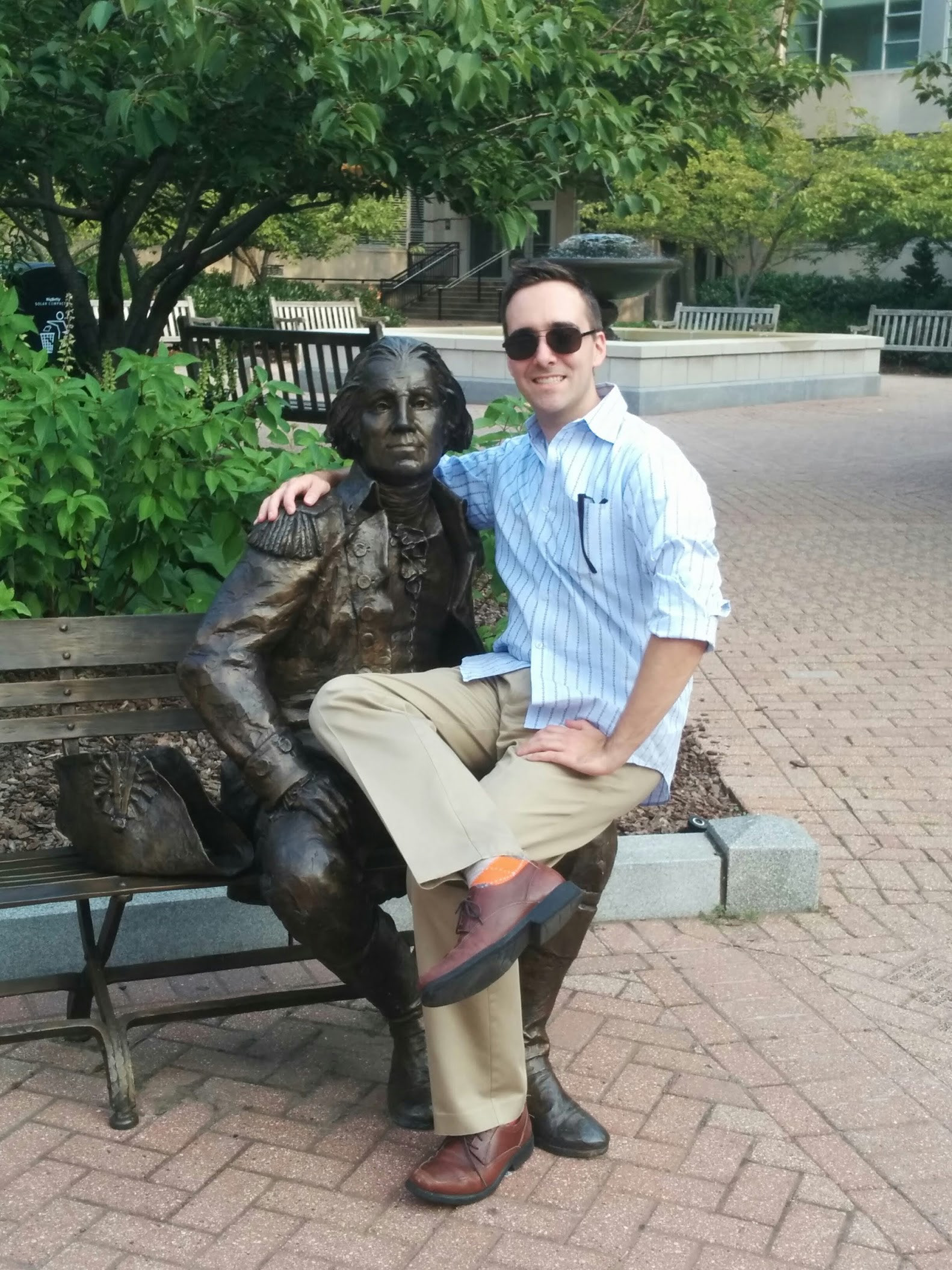 Sean Heavey sitting on the lap of a statue of George Washington at George Washington University.