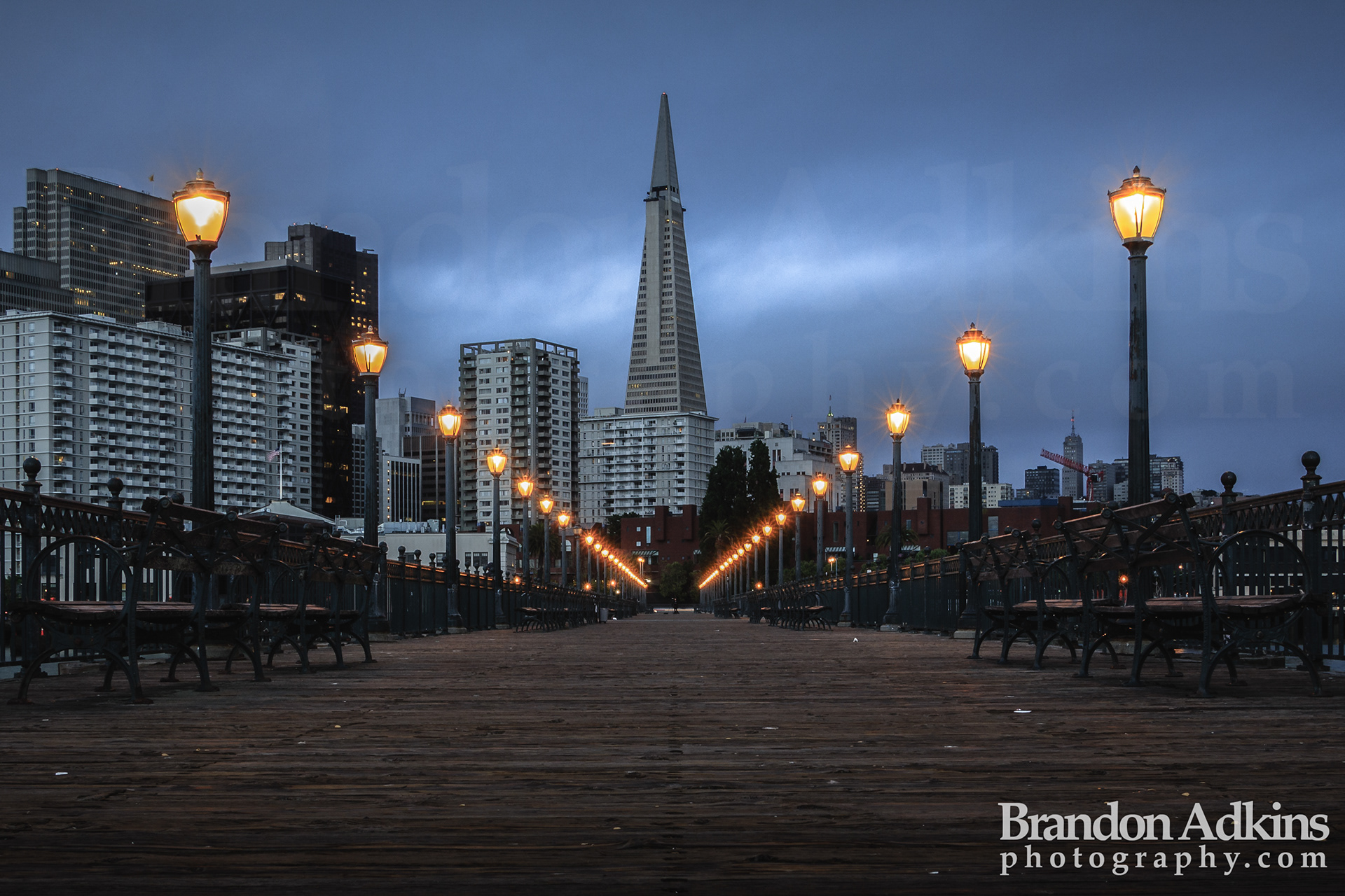Fine art photograph of pier with Transamerica Pyramid in the background and moonlit clouds in San Francisco, California