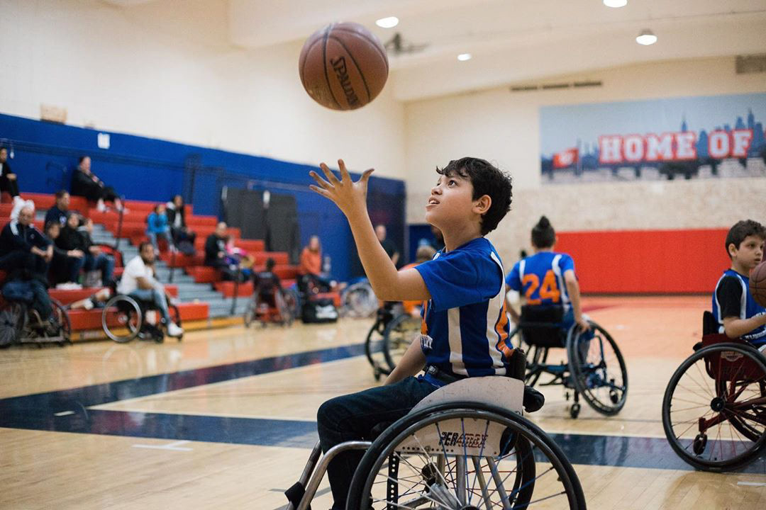 Child in a wheelchair catching a basketball at the Fitzgerald Gym