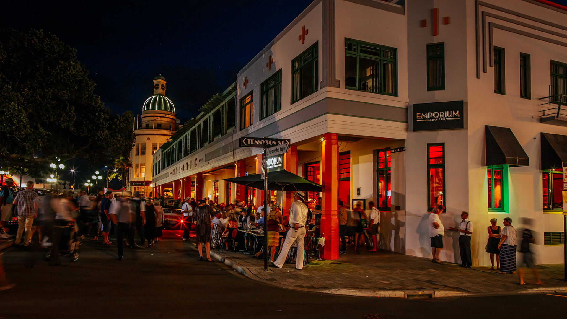 Night view of the Art Deco Masonic Hotel with lights and crowds of people enjoying the festivities
