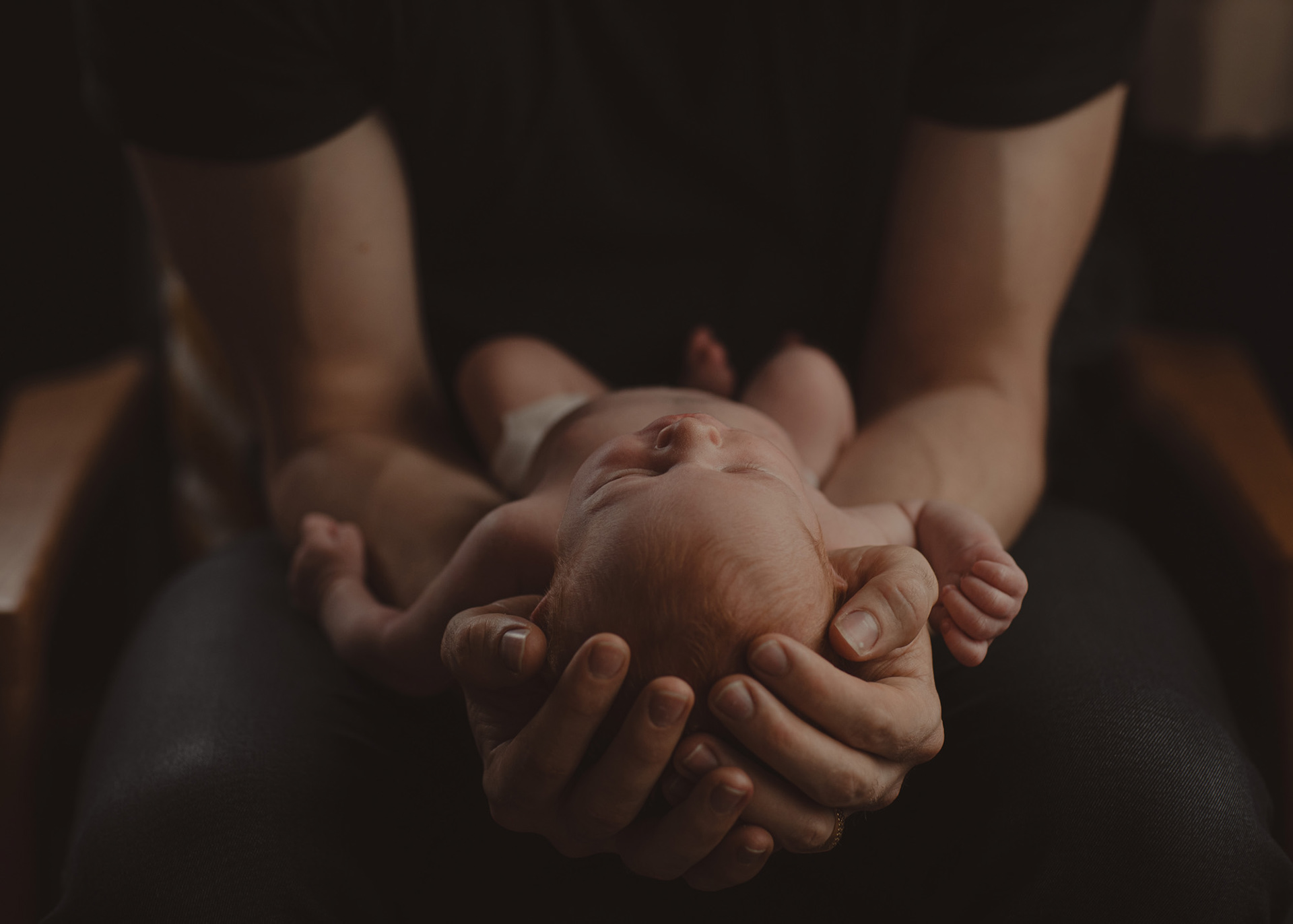 Newborn Torin being cradled in his dad's hands