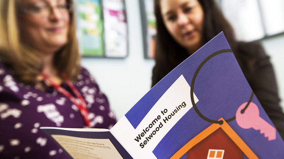 A young user reading the Welcome to Selwood Housing brochure