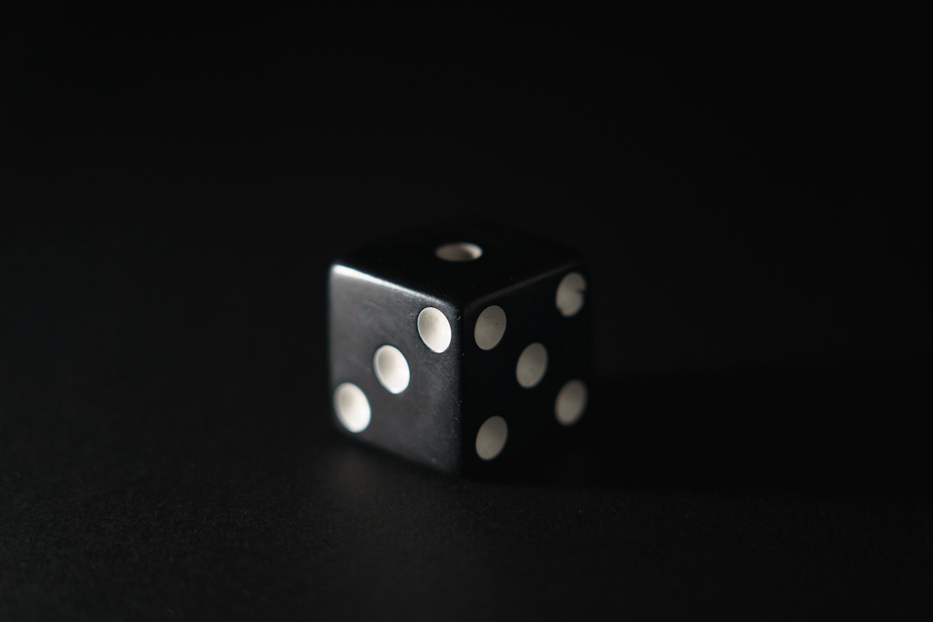 Side Lighting:Dice on black paper, 20201107, MILLER, Utilizing the black backdrop I was able to get a dramatic outline of the dice utilizing side lighting. Even though the dice is black on black paper, the lighting and my use of reflective lighting on the right side of the dice, allows it and its edges to been seen on the black paper, while still keeping the paper black and not washed out. Camera Settings: Sony A7II, ISO 200, 105mm, f4.5, 1/15s