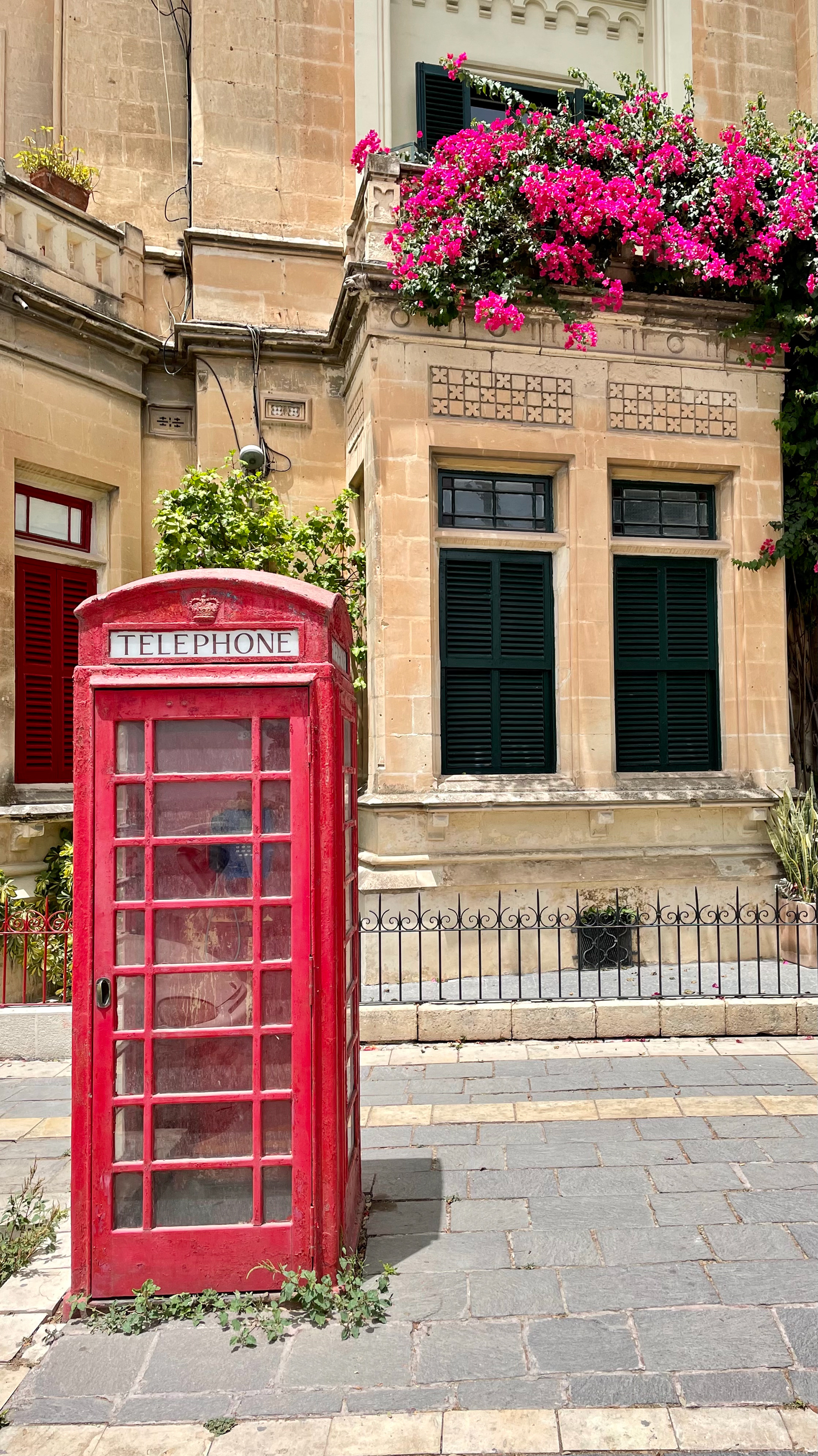 A red telephone box outside of the city by the bus station