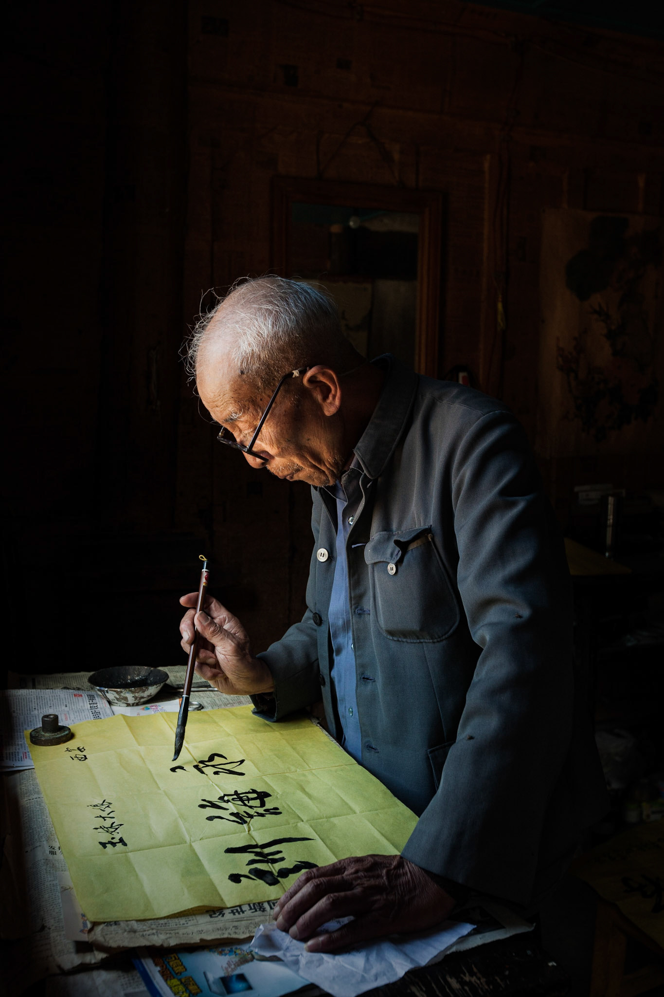 A Chinese Calligrapher making signs using traditional calligraphy in his shop in Shaxi, Yunnan Province, China.