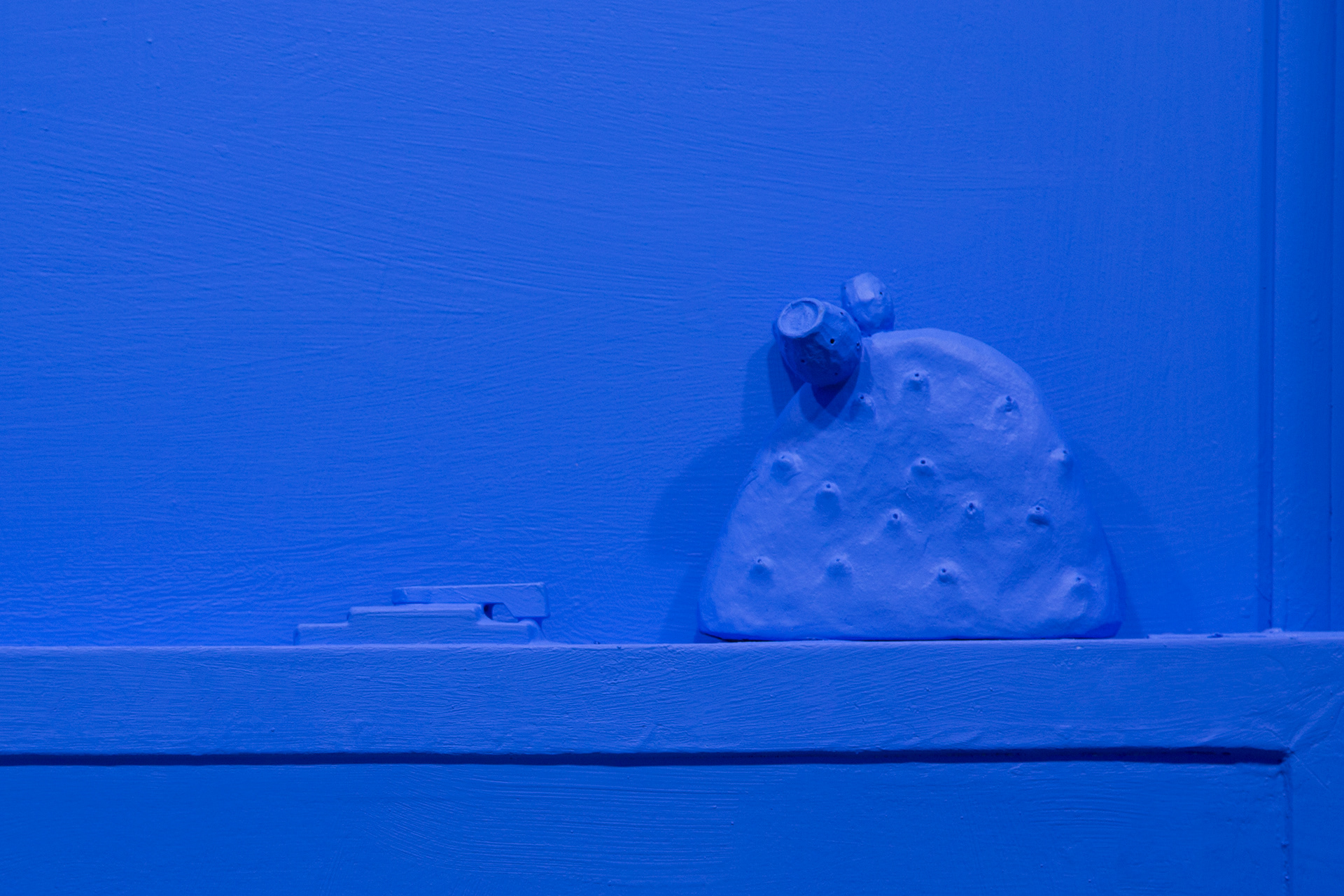 Close up detail of "Paradise of Greenery" showing a ceramic blue cactus sitting on a window ledge.