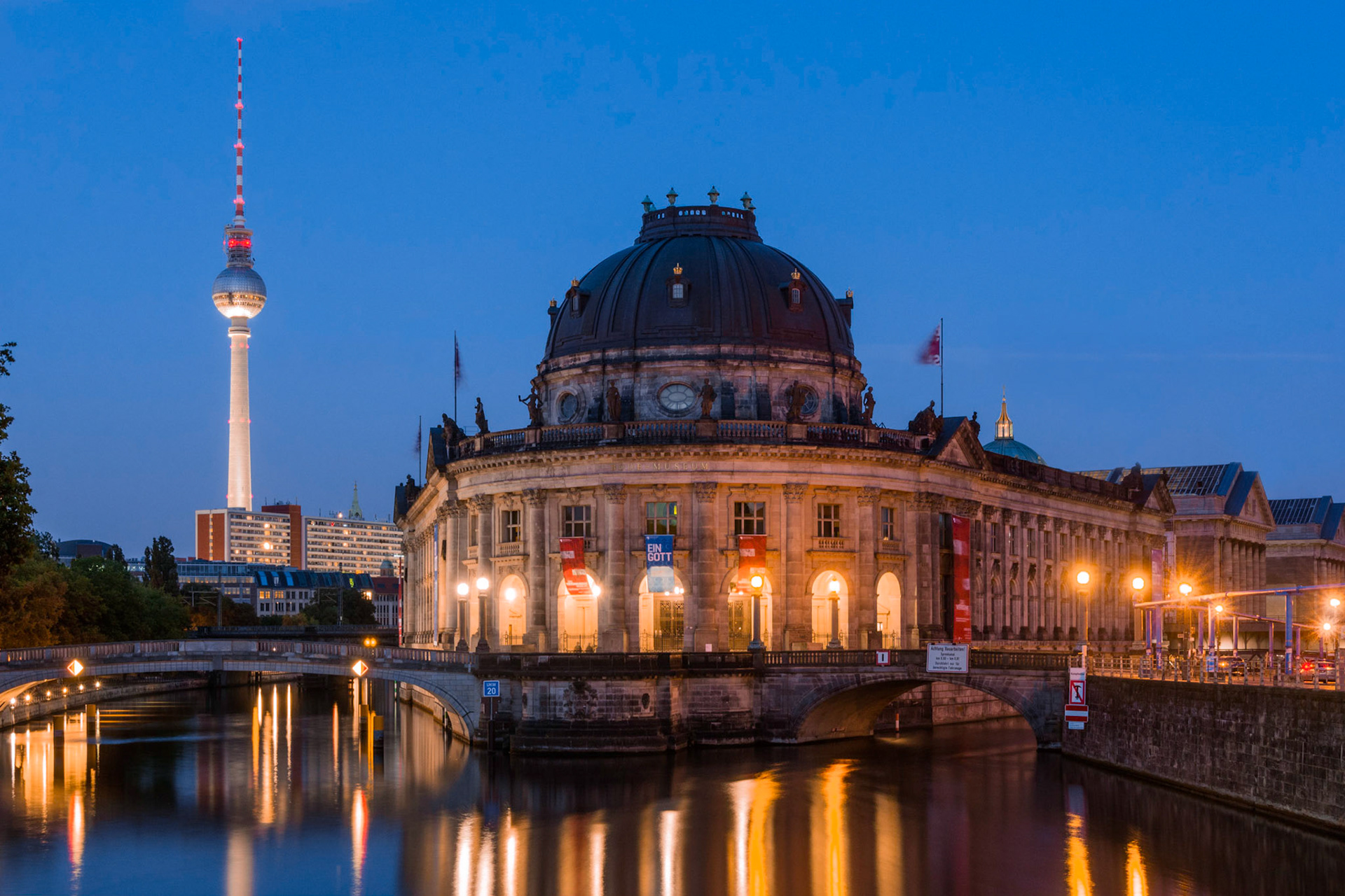 A view of Berlin's Museum Island and the TV Tower at dusk, reflecting in the Spree River