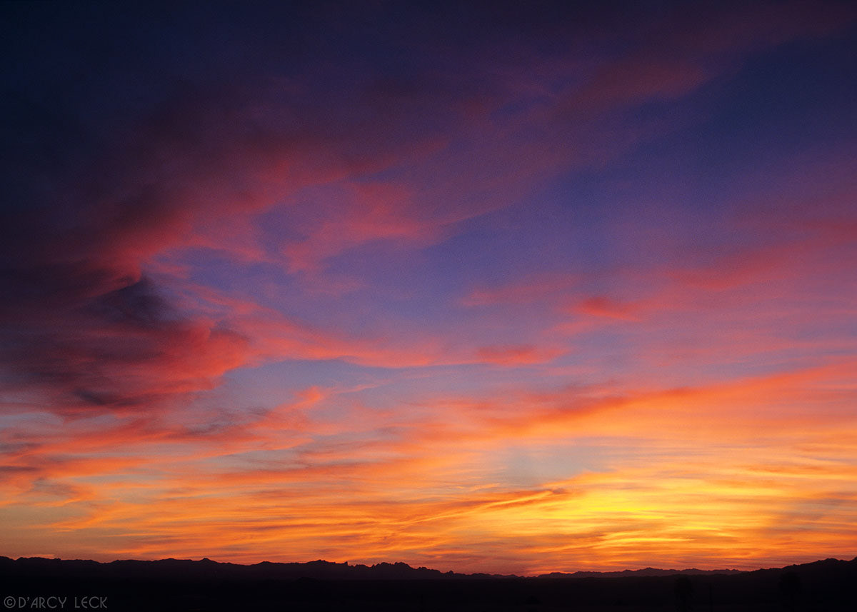 High clouds at dusk painted in sunset colors over mountains near Lake Havasu, California