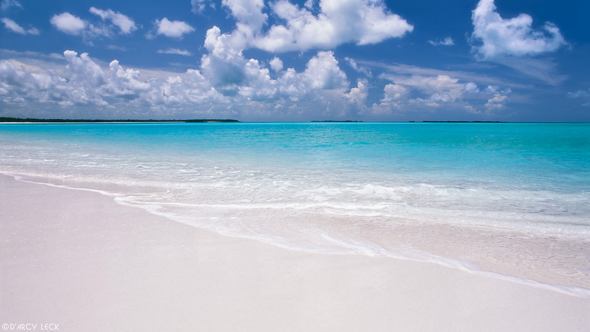 Surf laps a white sand beach with aquamarine waters beyond at Treasure Cay, Bahamas
