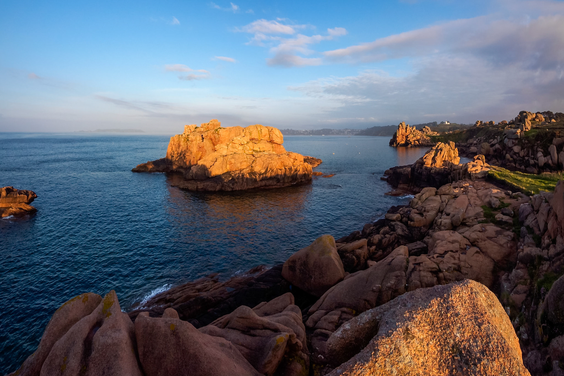Under a blue sky during a golden sunset, a small group of daredevil divers prepared to jump off this cliff in Ploumanach, Bretagne.