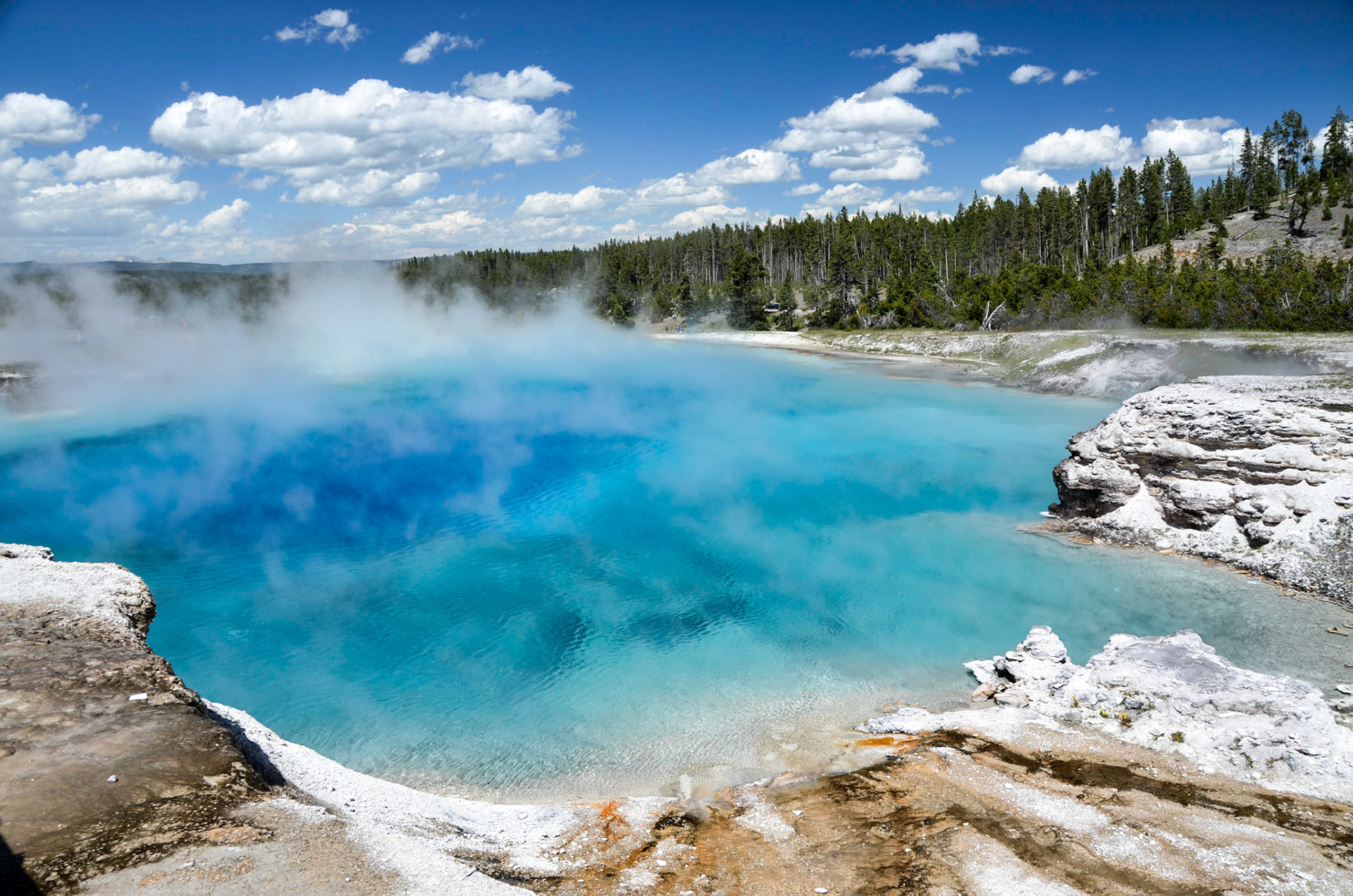 Steam rising above the bright blue water of Excelsior Geyser Crater, Yellowstone National Park, Wyoming