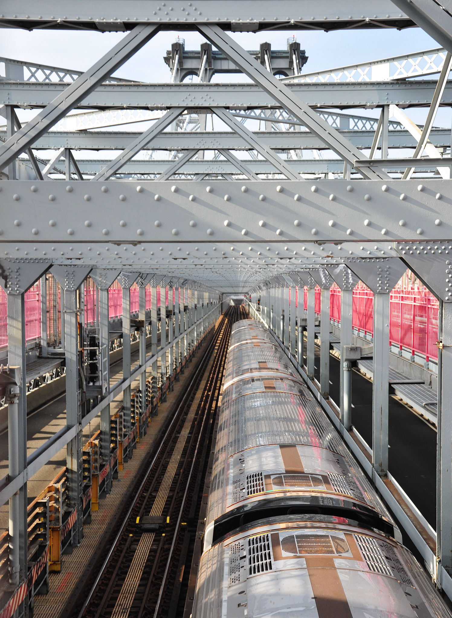 J Train crosses the Williamsburg Bridge from Brooklyn to Manhattan.  The Williamsburg Bridge carries subway trains, automobiles, bicycles and pedestrians year round, 24/7.