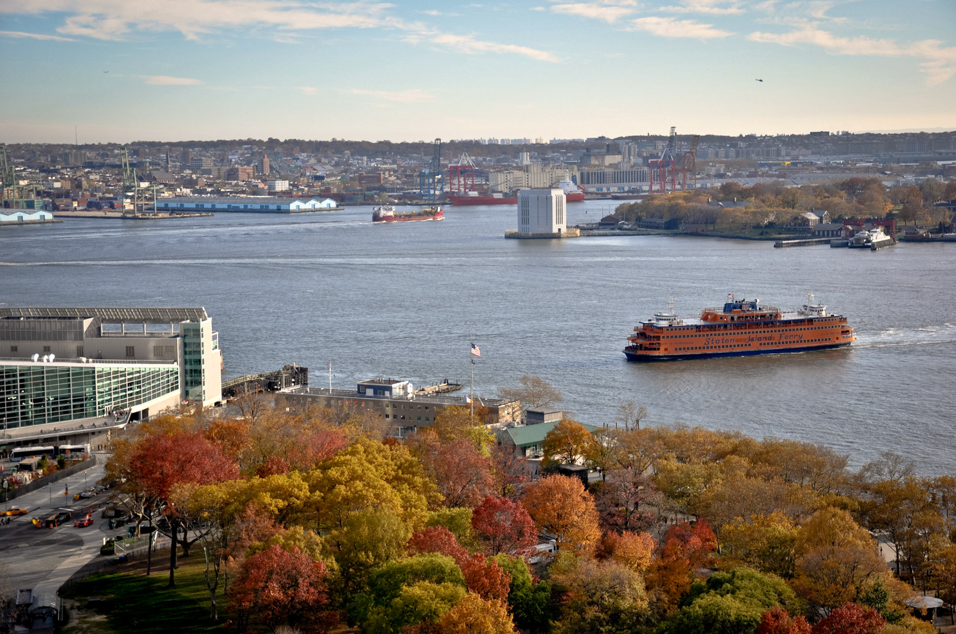 Lower Manhattan - New York, NY  //  Battery Park is colored red, yellow and orange.  The Staten Island Ferry approaches the Manhattan Terminal. The trees of Governor's Island can be seen to the right across the river.  Brooklyn is in the distance.  Brooklyn's Prospect Park's tree tops are in the background on the horizon.  //  11/2010