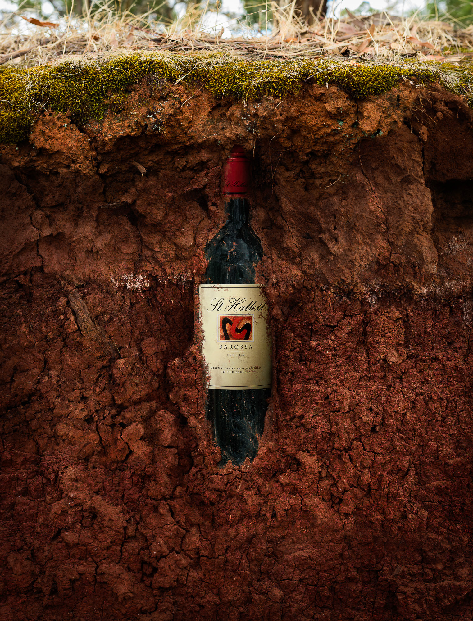 St Hallett Red Wine bottle buried in terra rosa soil. Creative retouching by Paul Munzberg.