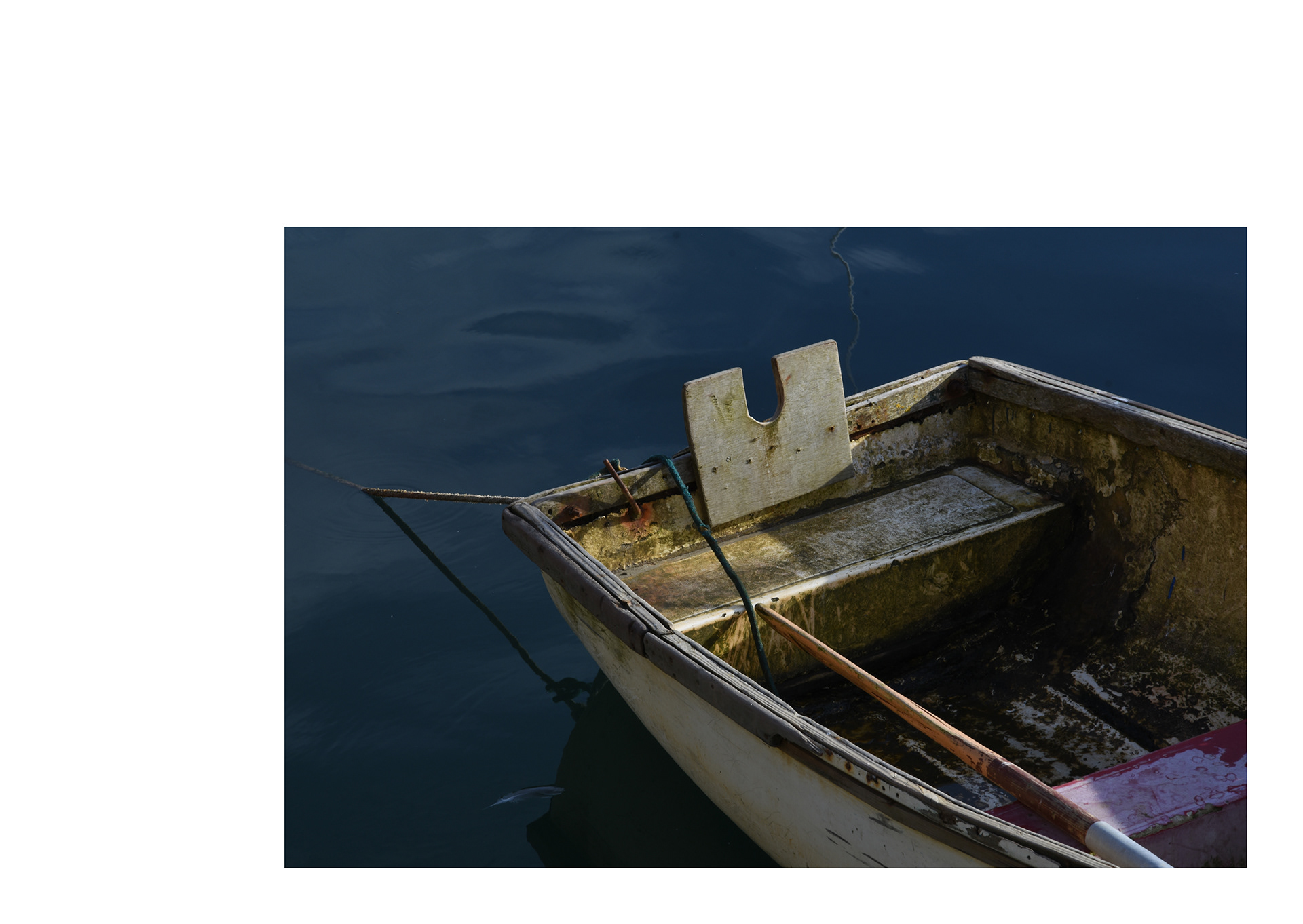 dirty row boat in Mevagissey harbour in Cornwall by freelance photographer in cornwall