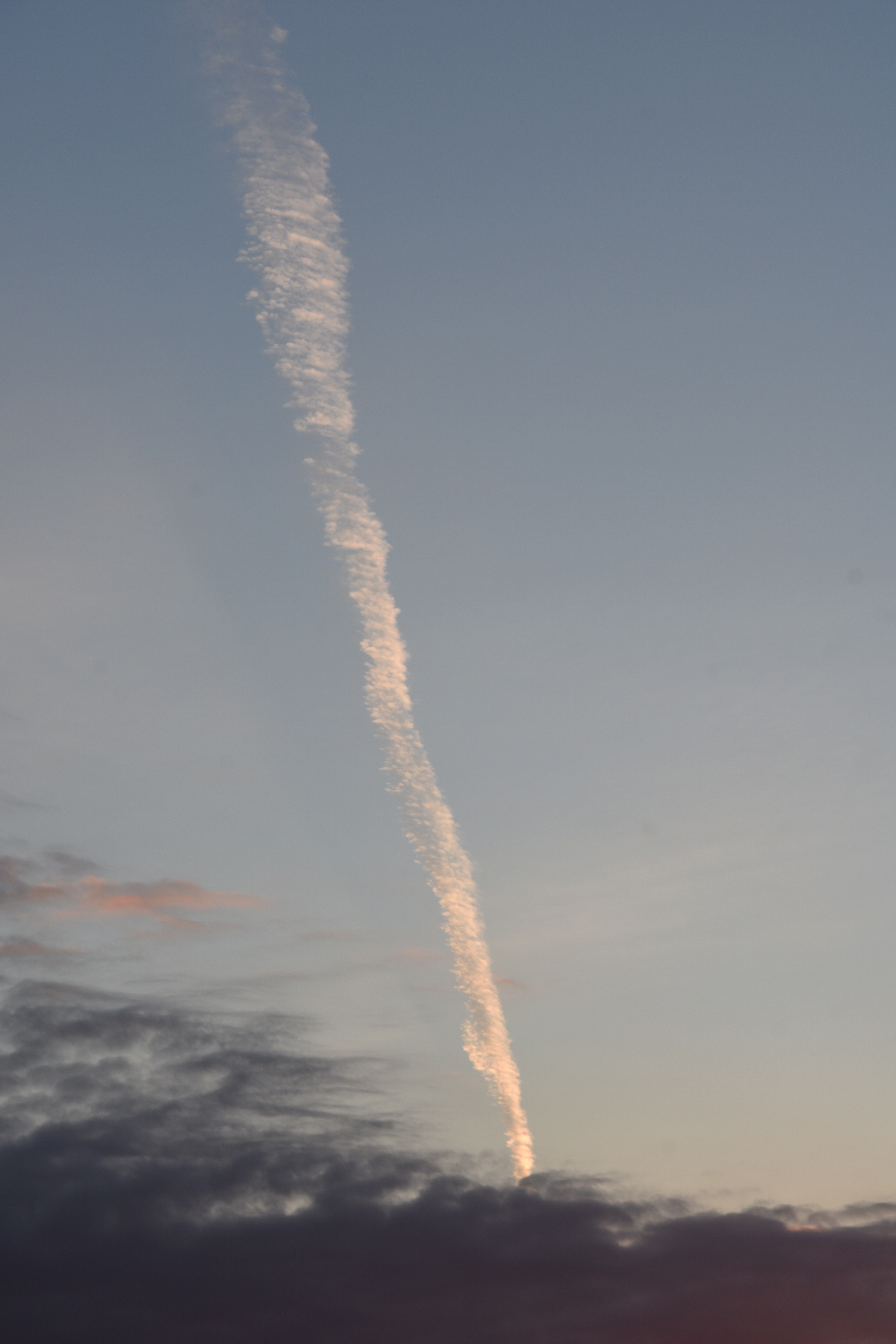 airplane trail and clouds in the sky in cornwall by photographer melissa carne