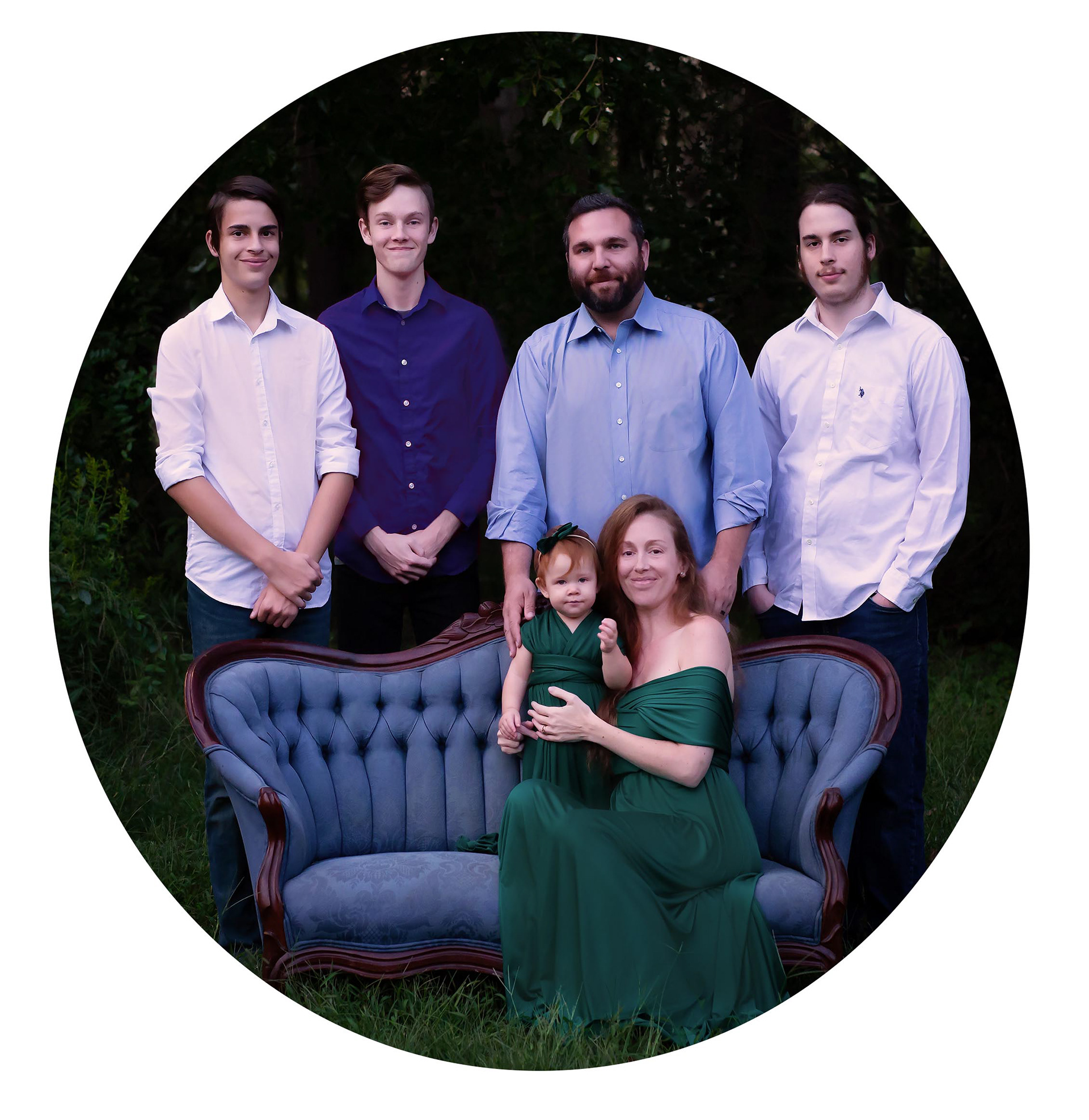 Photographer and her family (a husband, 3 teenage sons, and a one year old daughter) sitting on a vintage sofa outside.